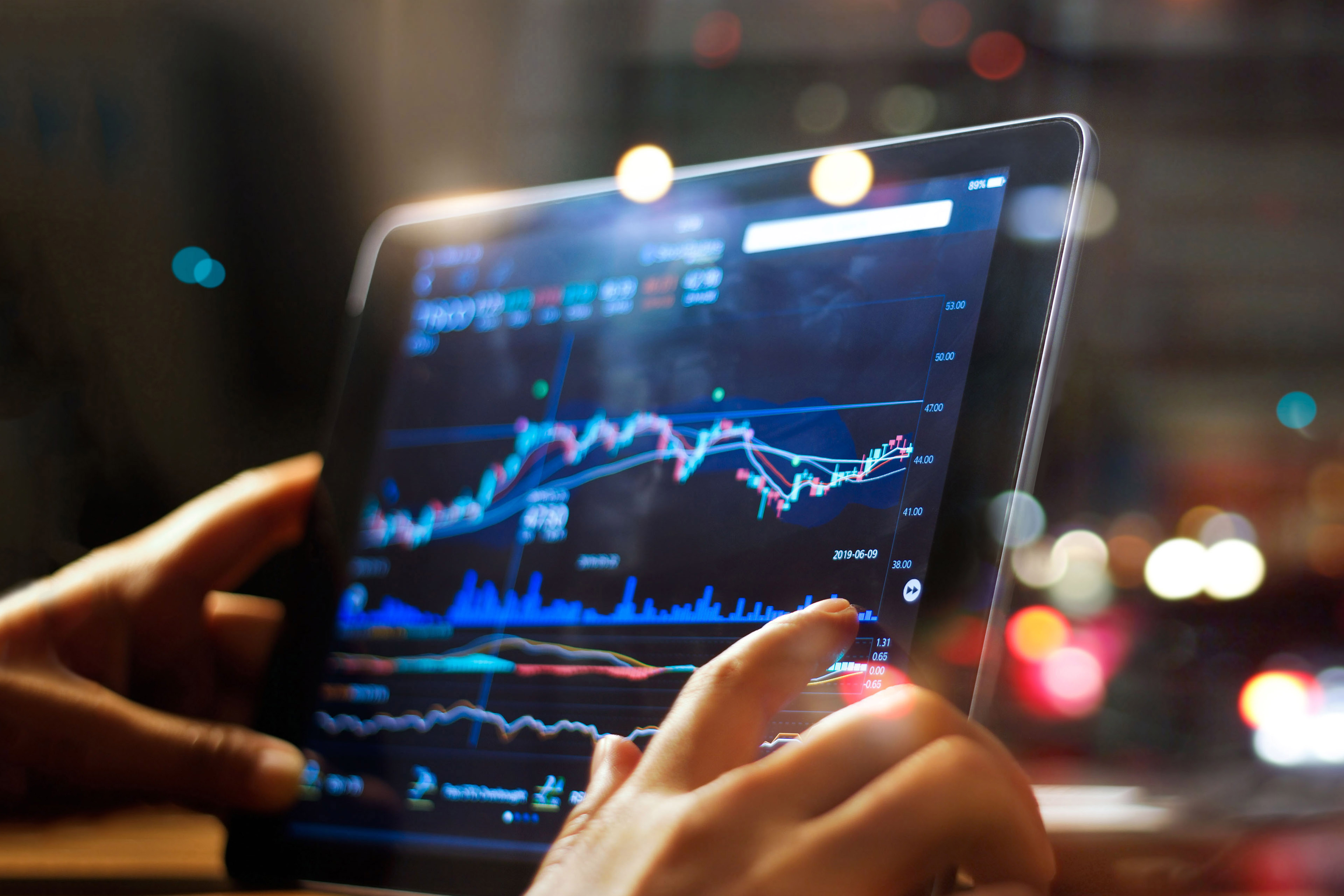 Businessman checking stock market data on tablet on night background