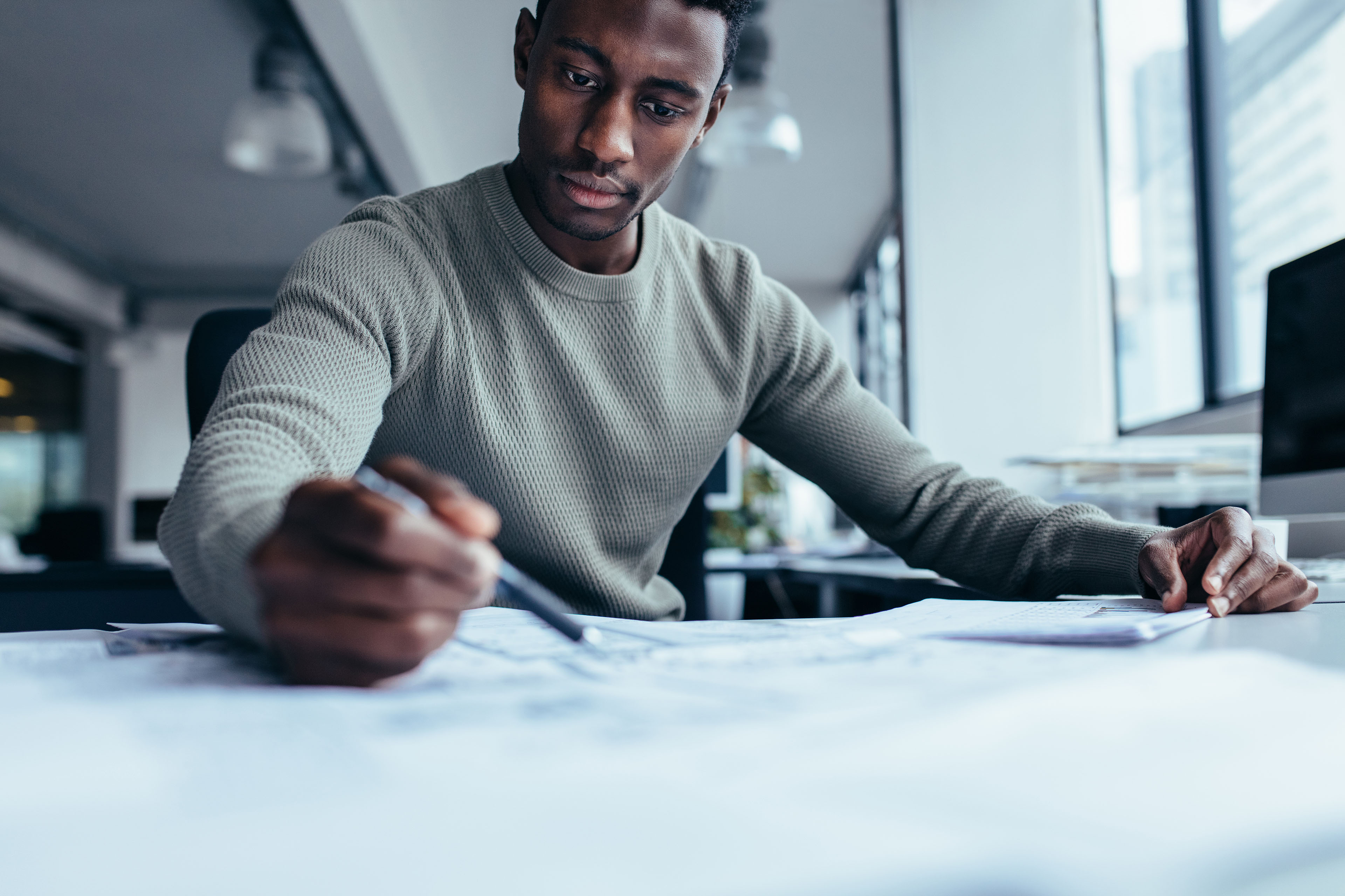 Businessman pointing at building plan in office