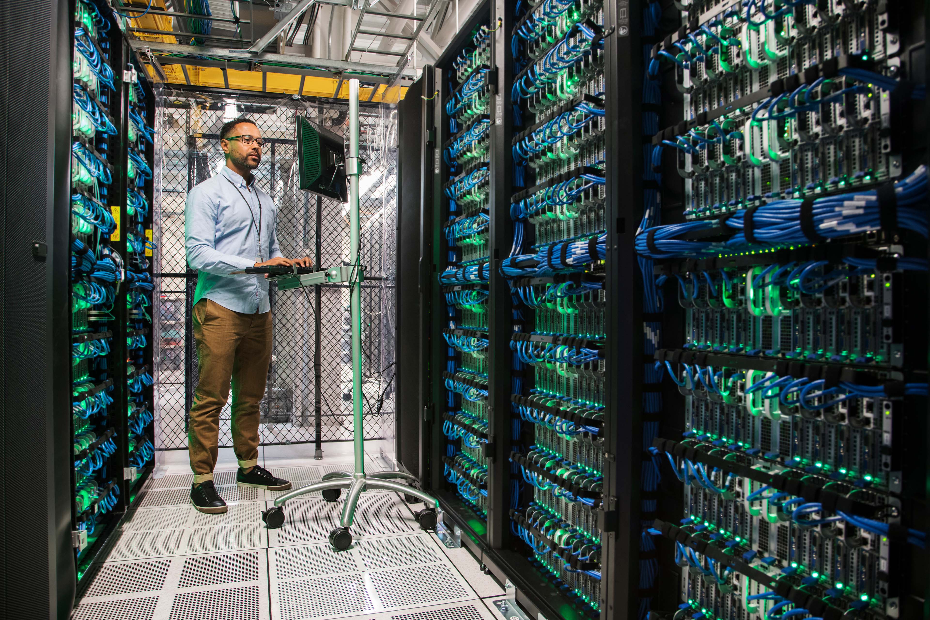 Mixed Race technician using computer in server room