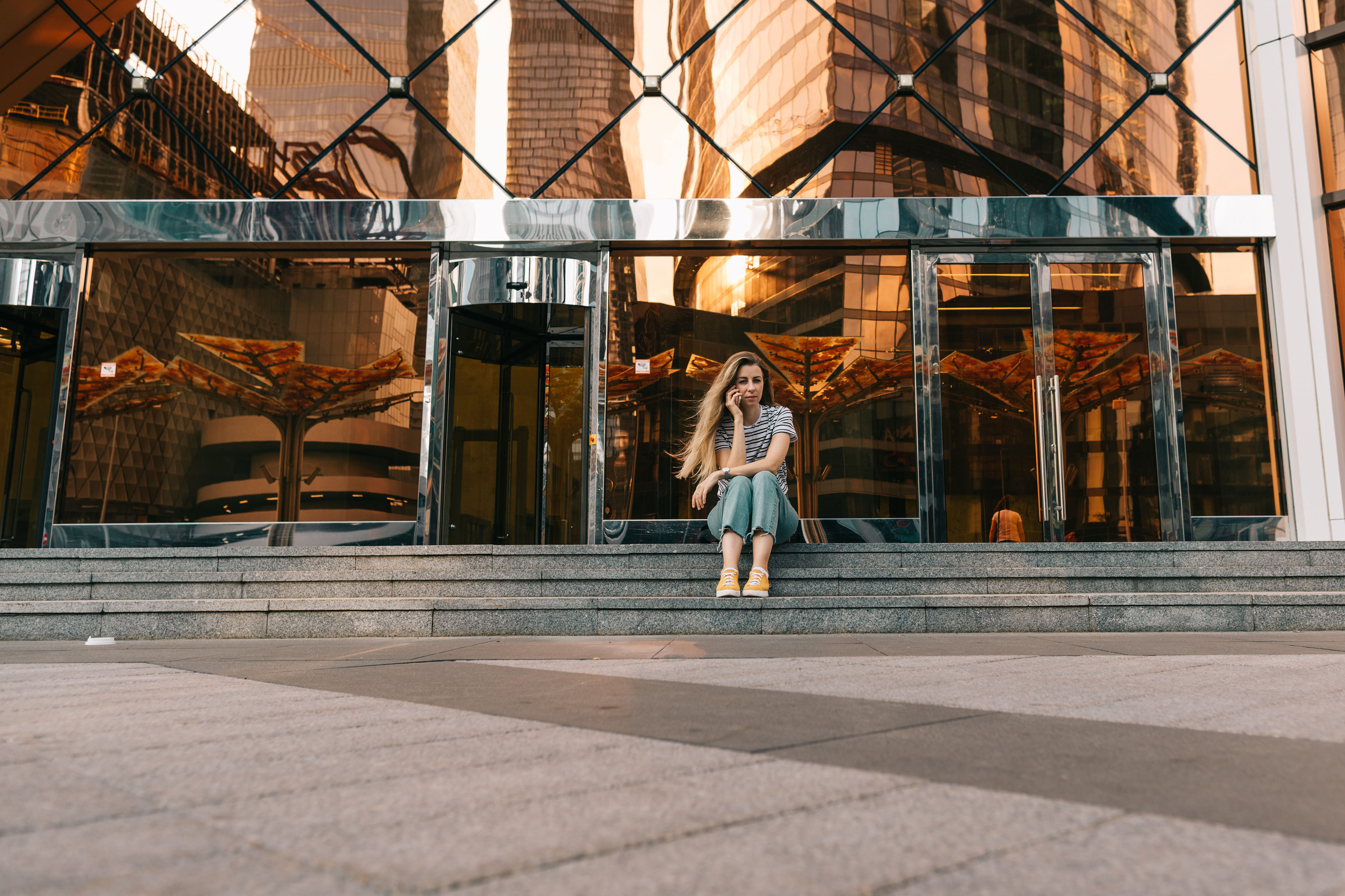 Woman sat on steps outside office building using her phone