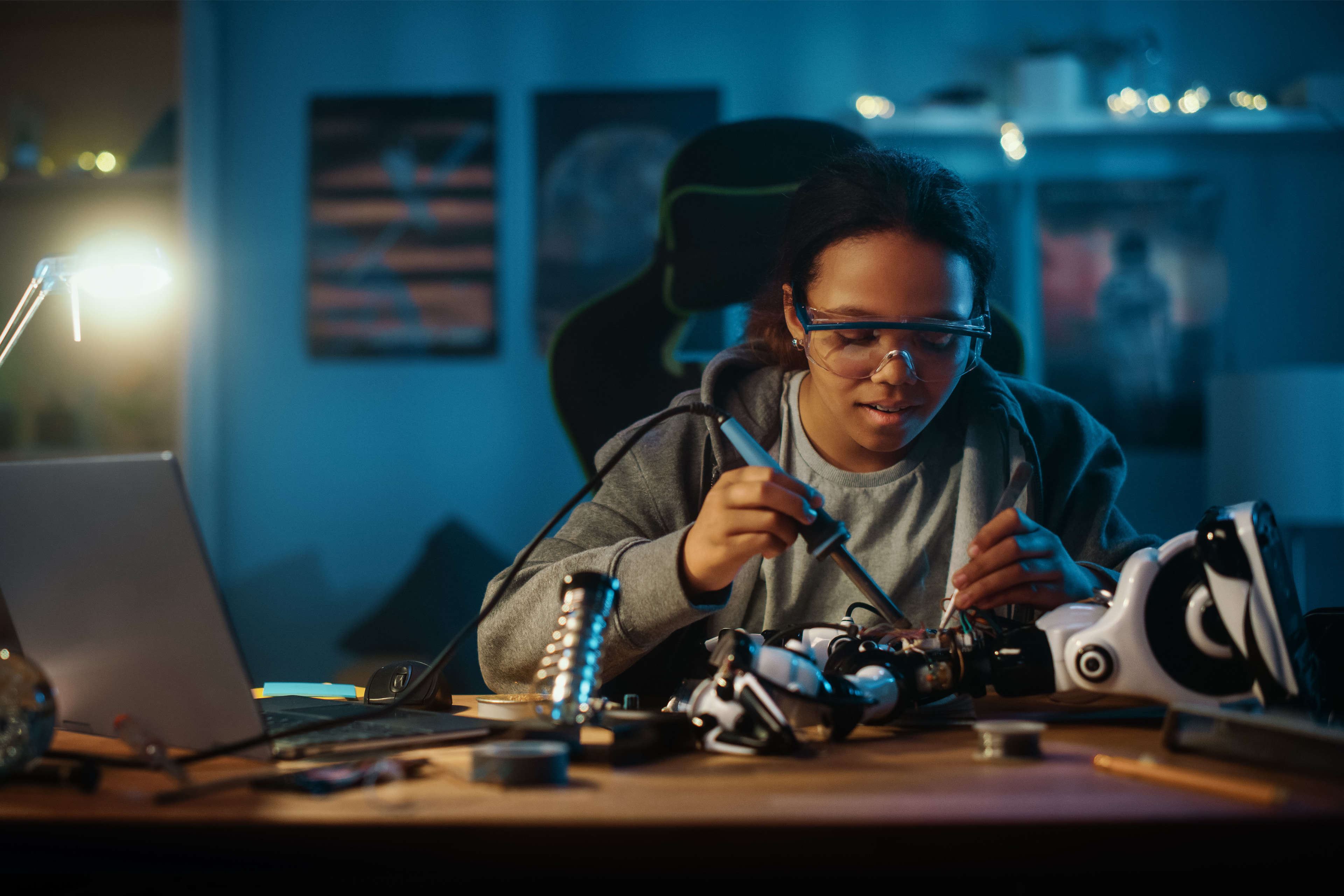 Young teenage multiethnic schoolgirl soldering wires and circuit boards