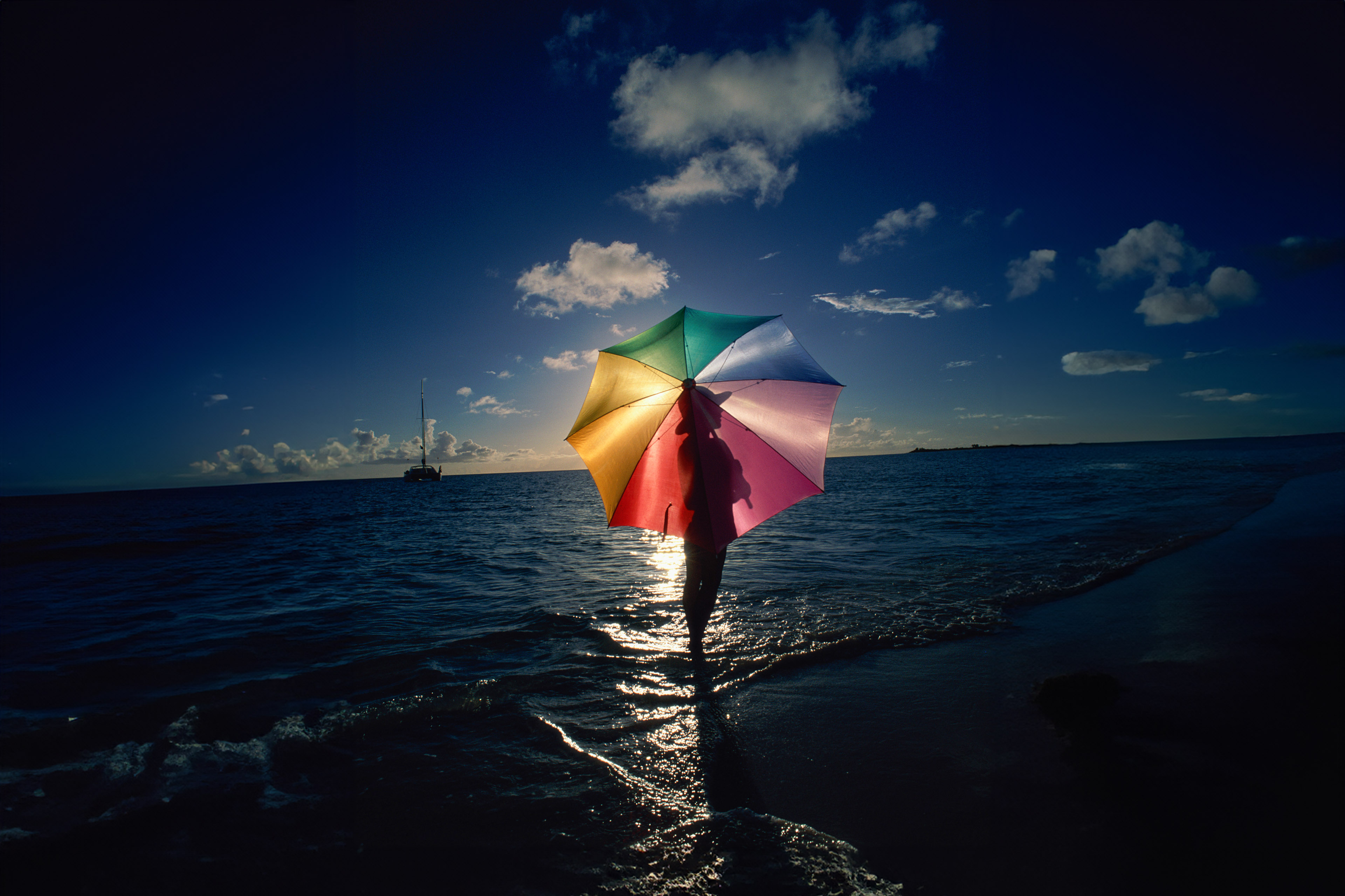 Woman standing on beach with umbrella on caribbean island