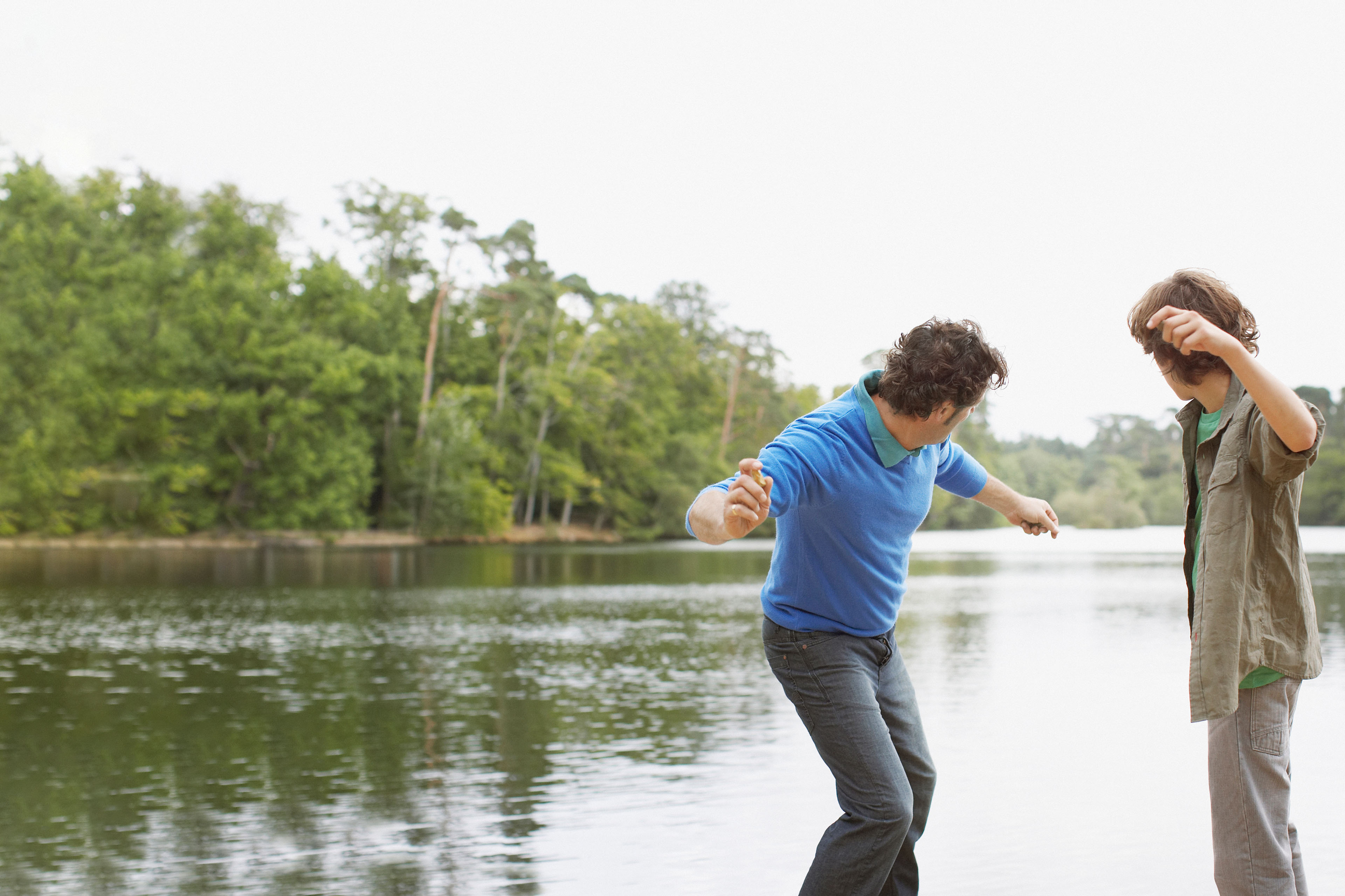 Father and son skimming stones in lake