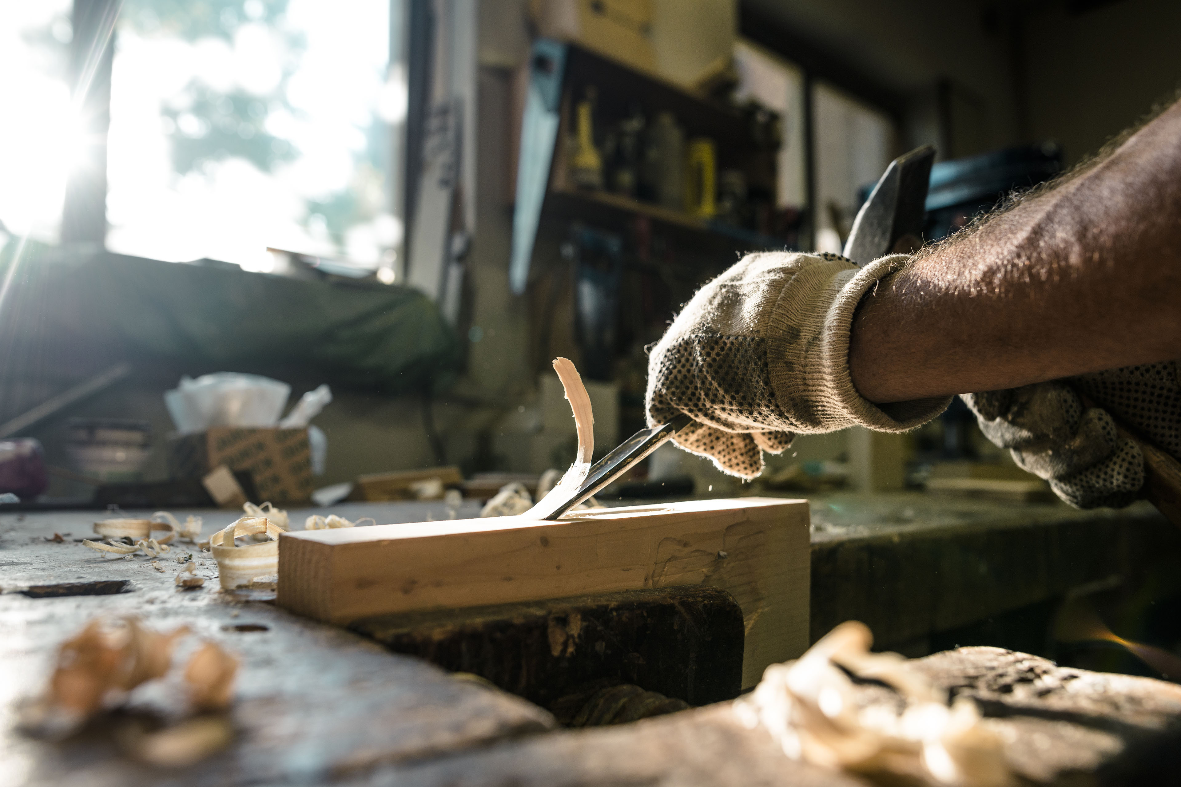 An experienced carpenter shapes wood with a chisel