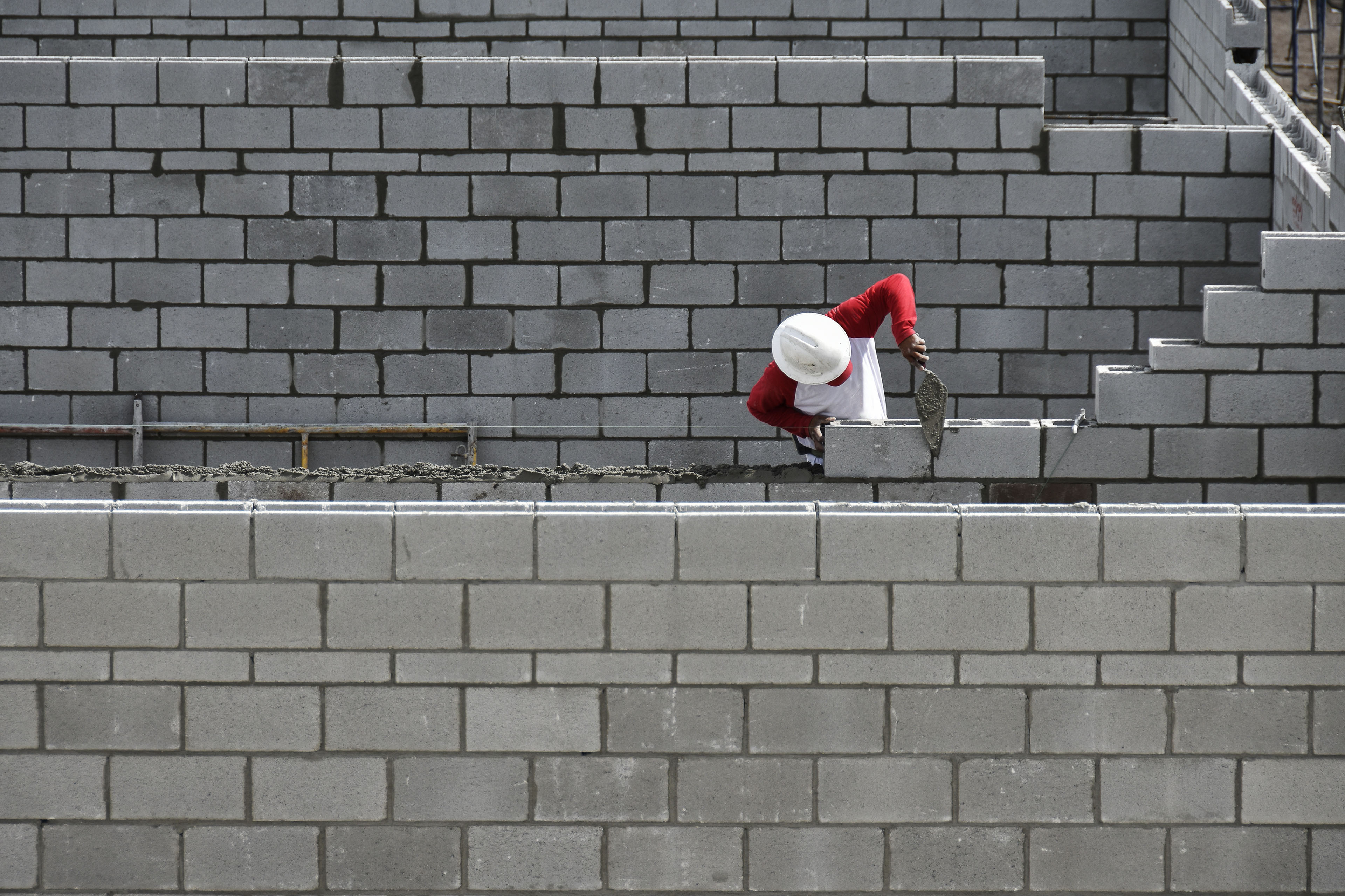 Un hombre construye un muro con capas de ladrillos.