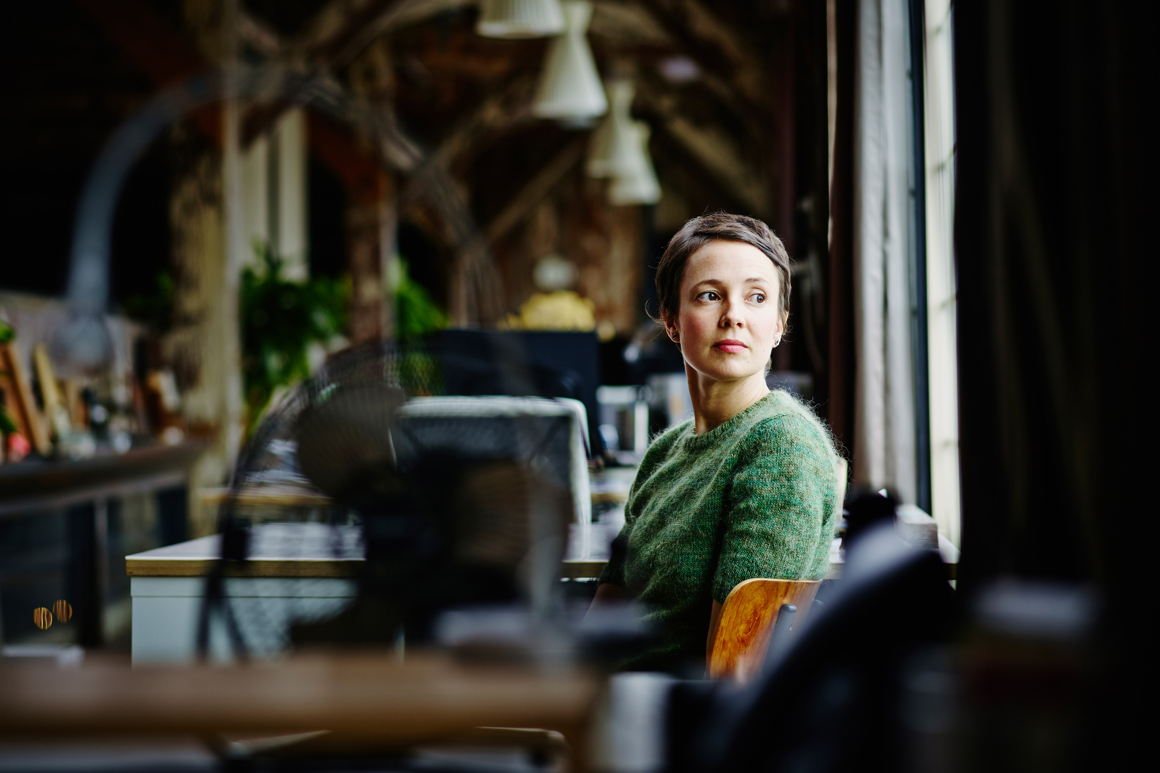 Businesswoman sitting at workstation looking out window