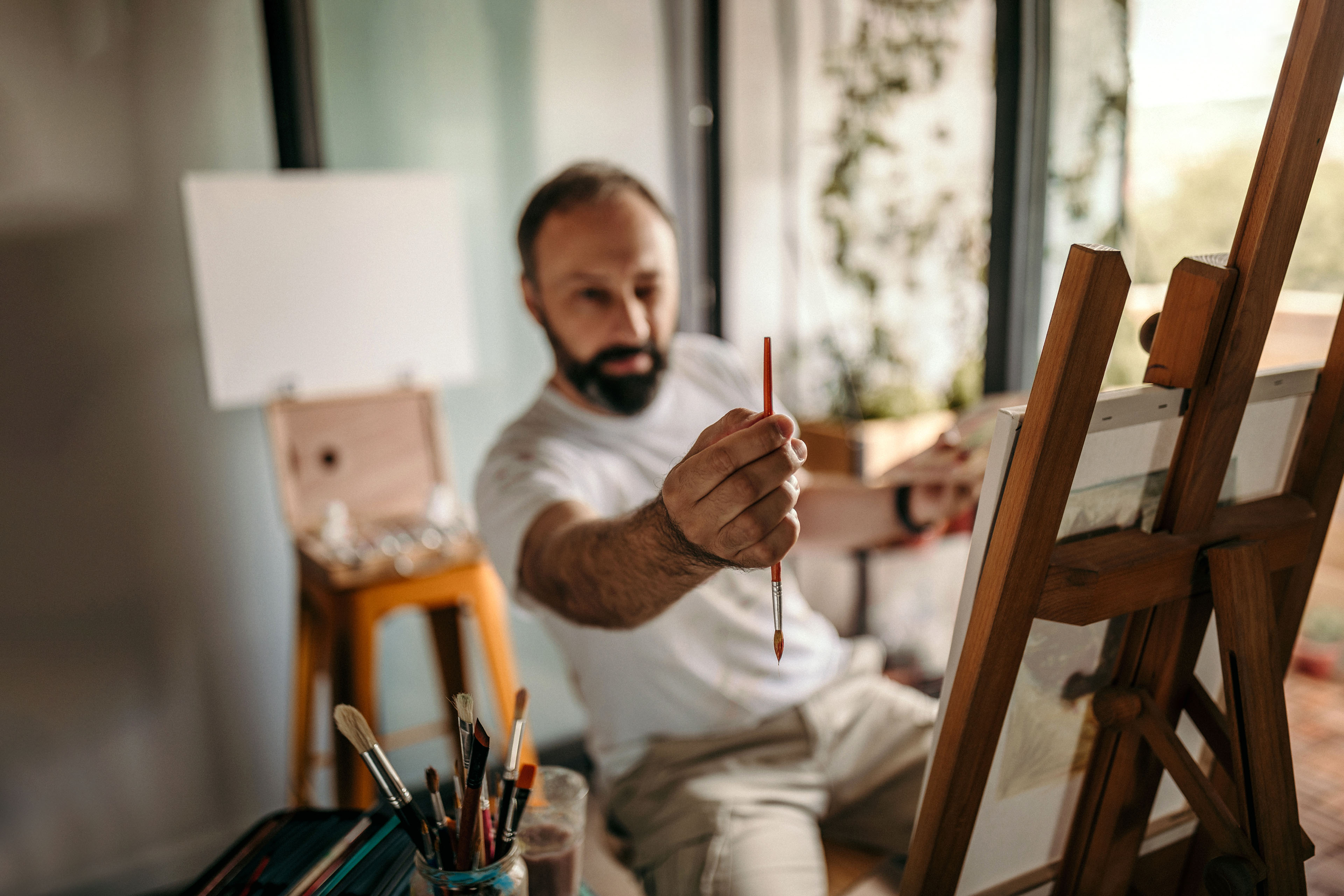 male artist measuring scale with paintbrush in studio