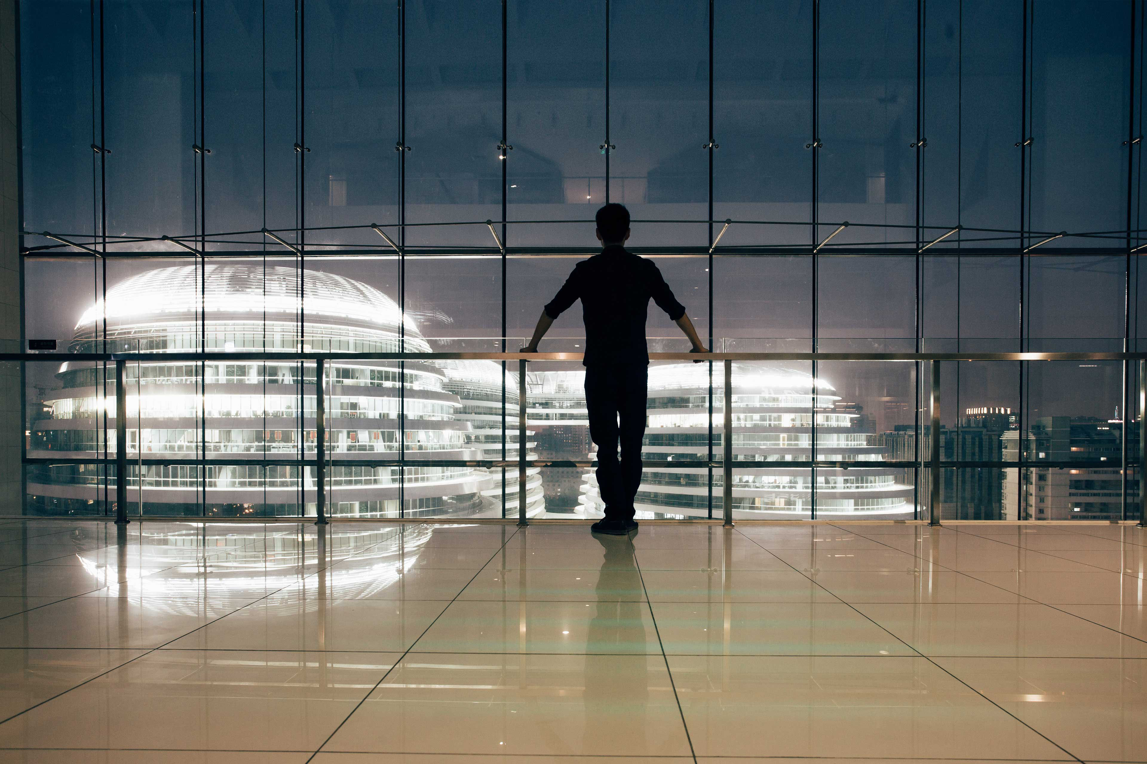 Man looking out window over city