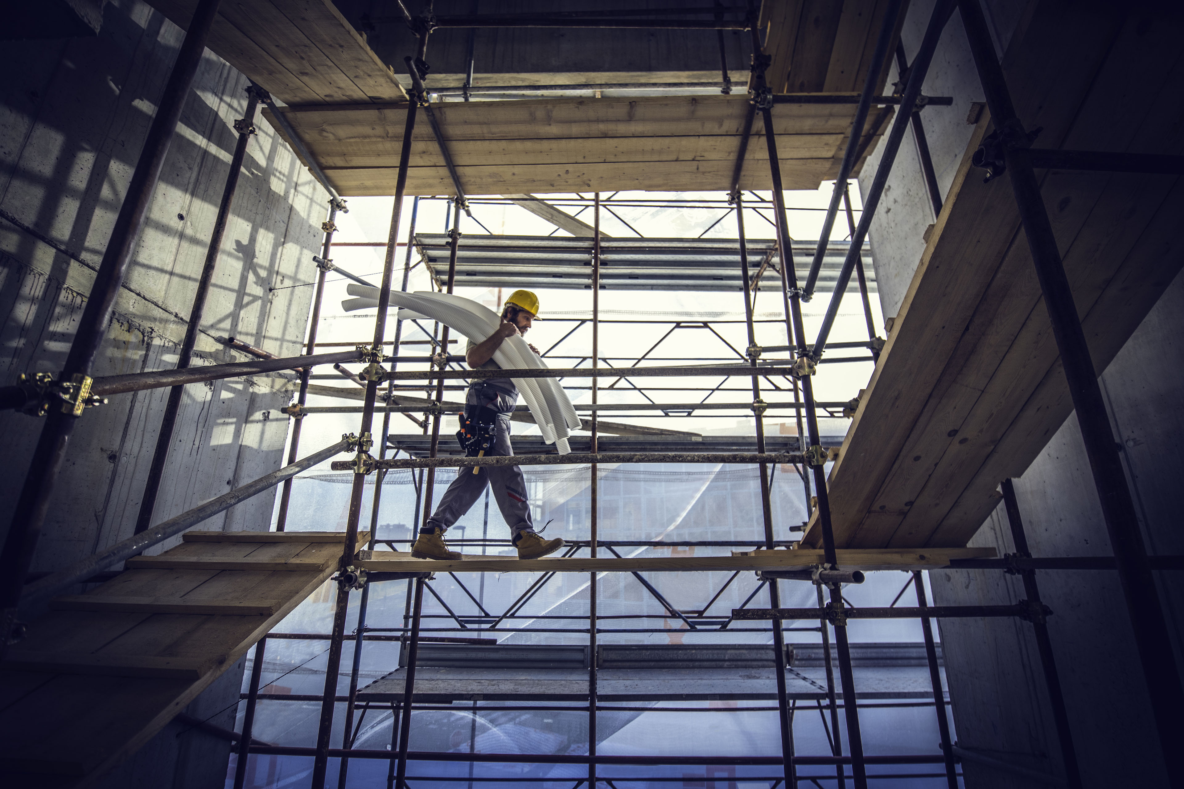 Worker carrying pipes