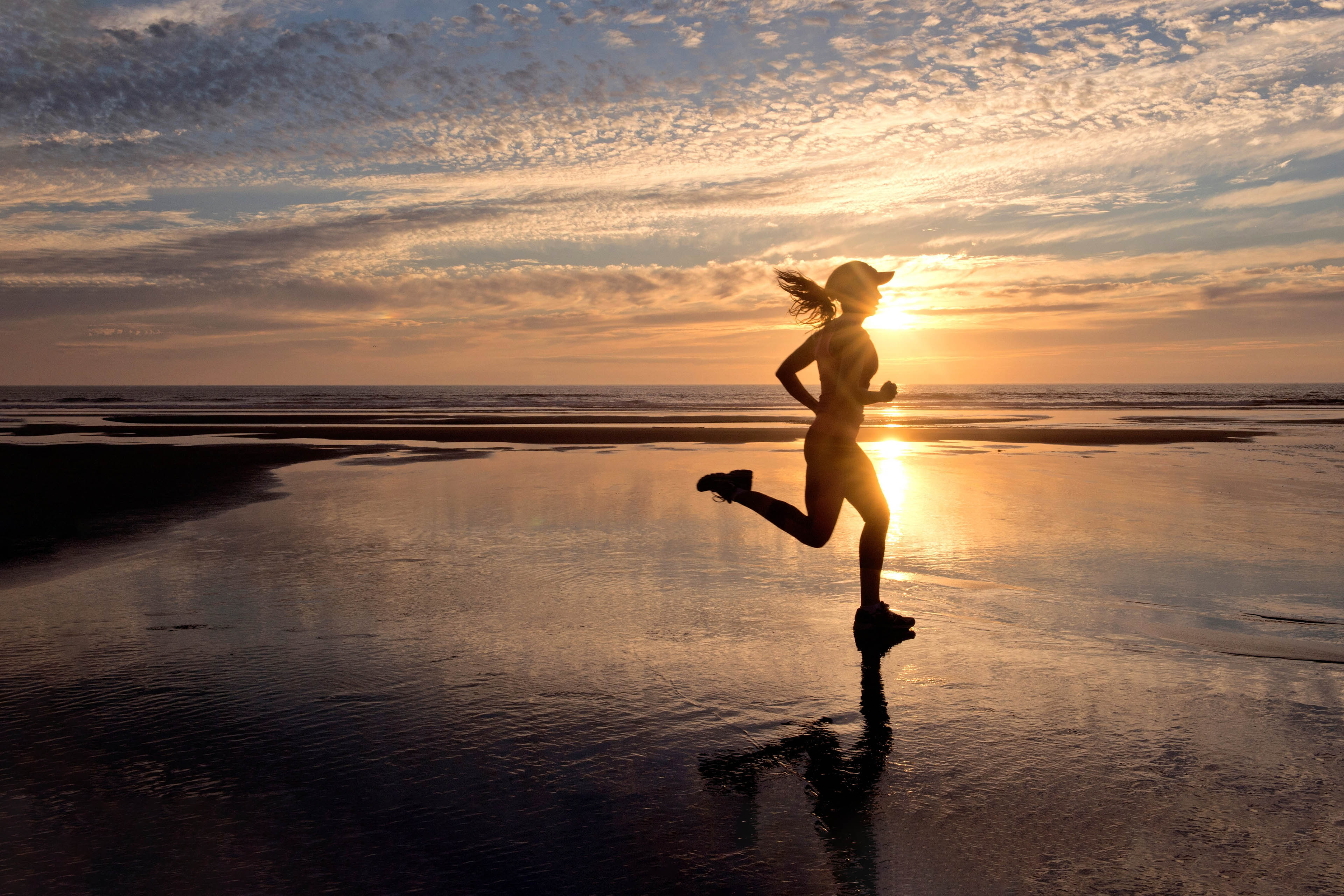 Woman running on beach at sunrise