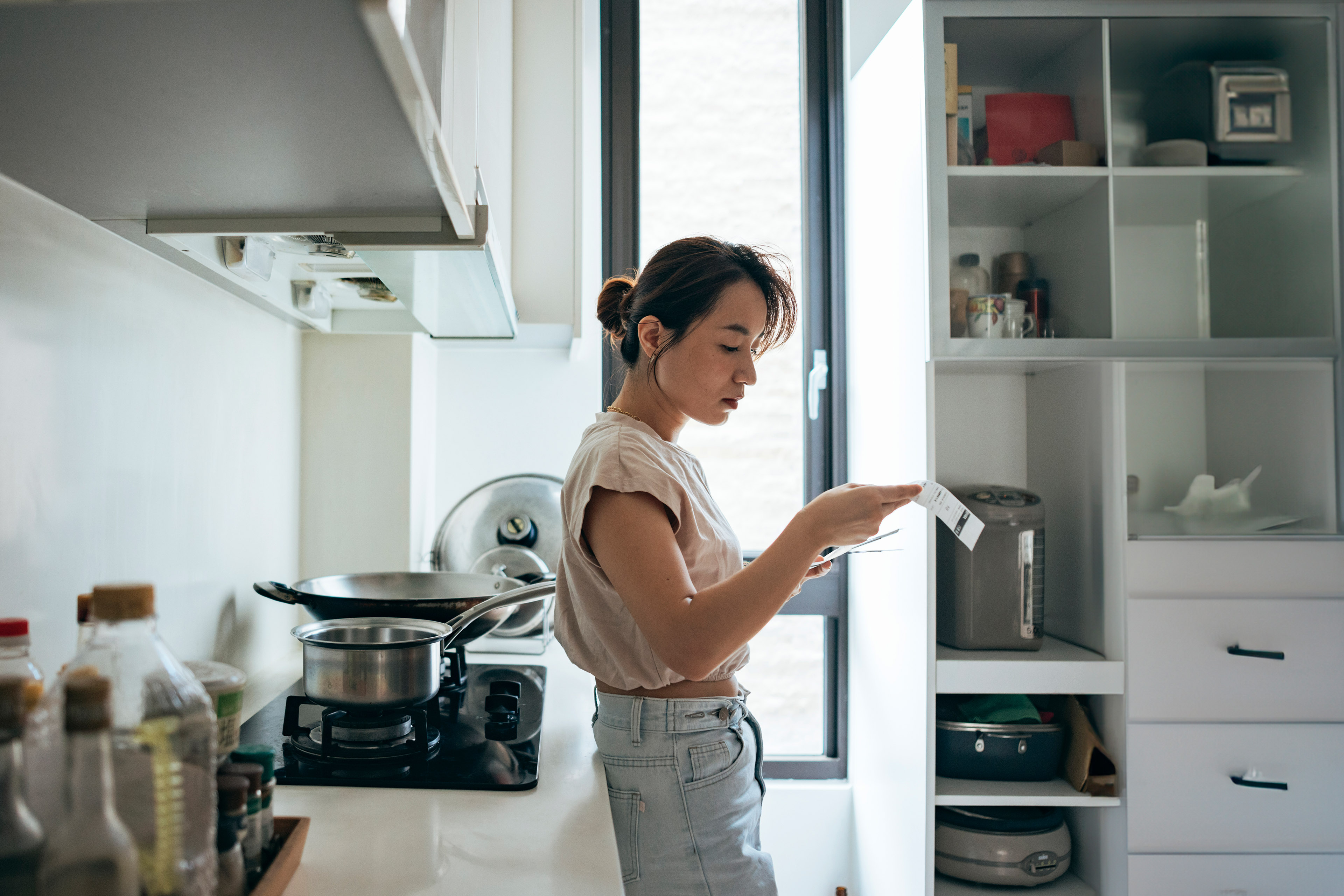 A photograph of an Asian woman examining a shopping receipt at home