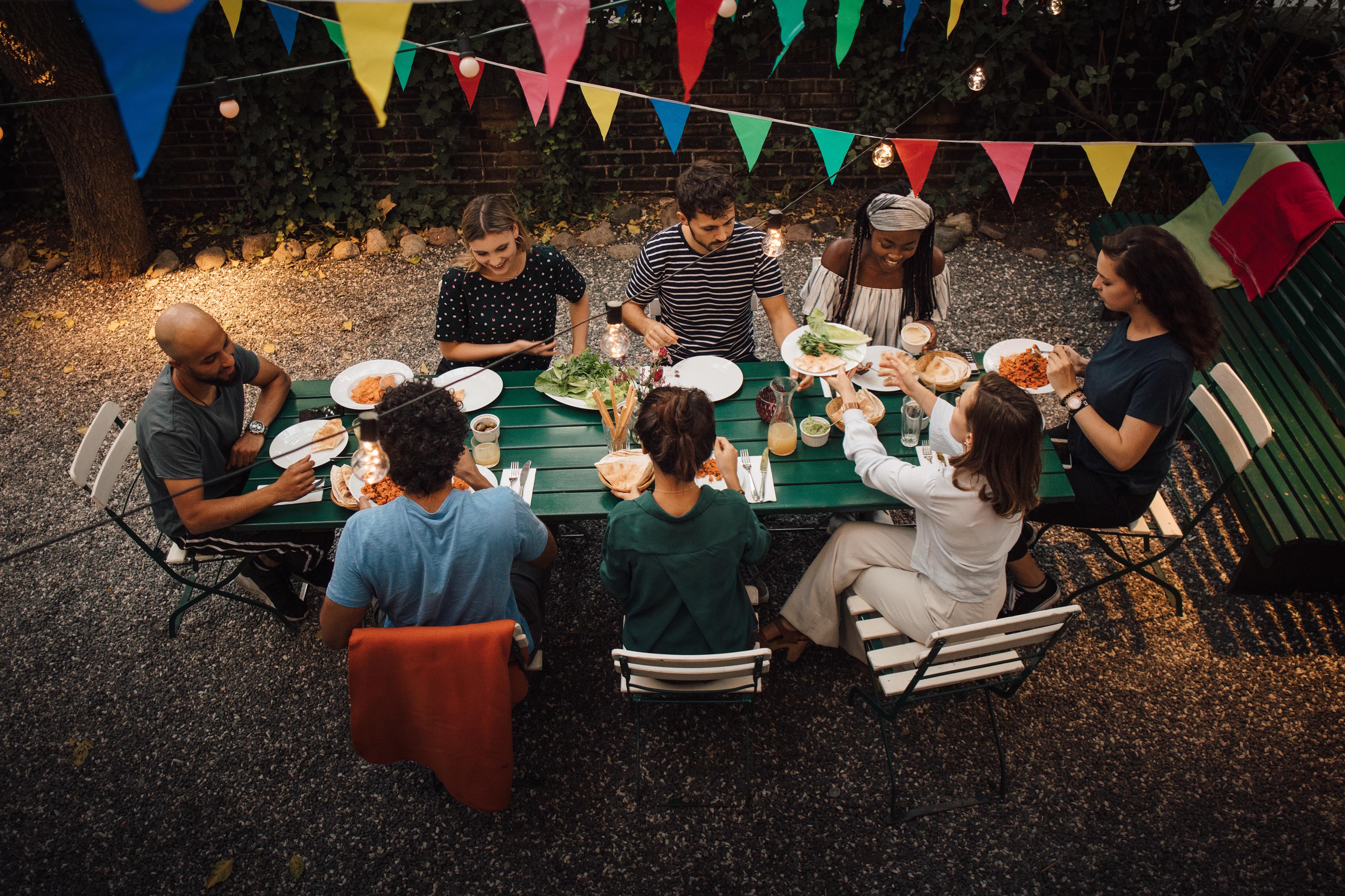 High angle shot of friends eating at a long garden table