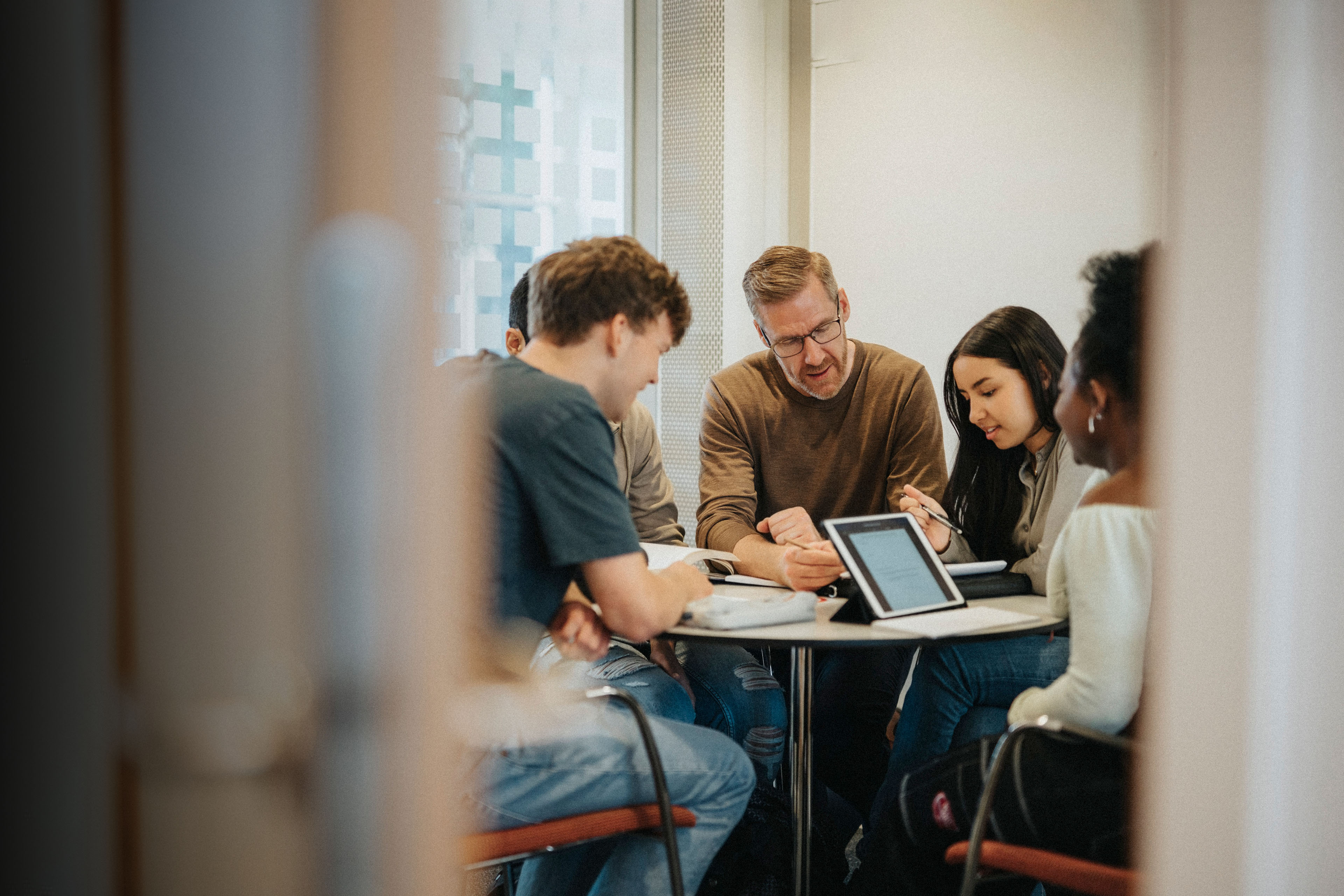 Mature male professor explaining to students at table in University