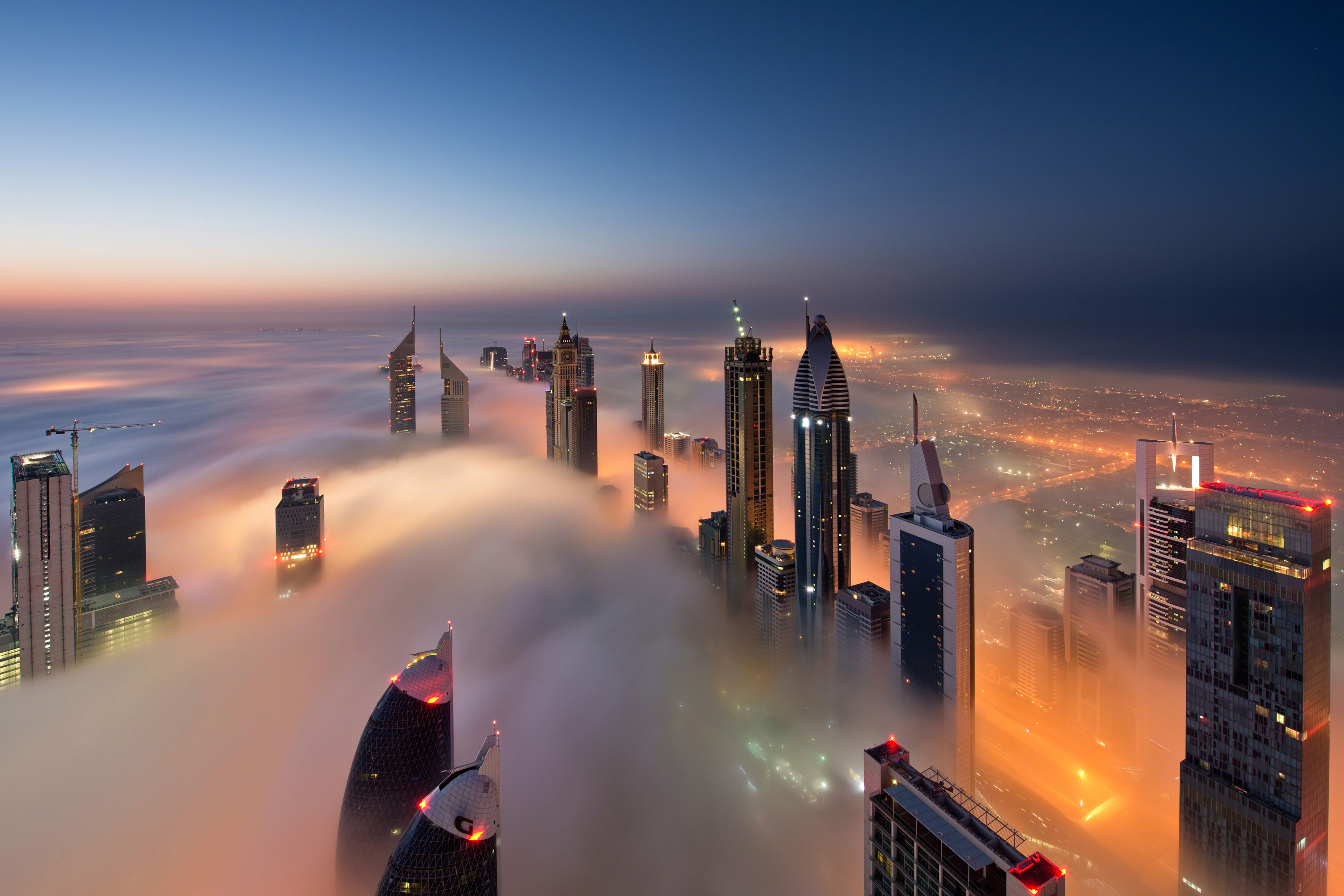 View of illuminated skyscrapers above the clouds in Dubai