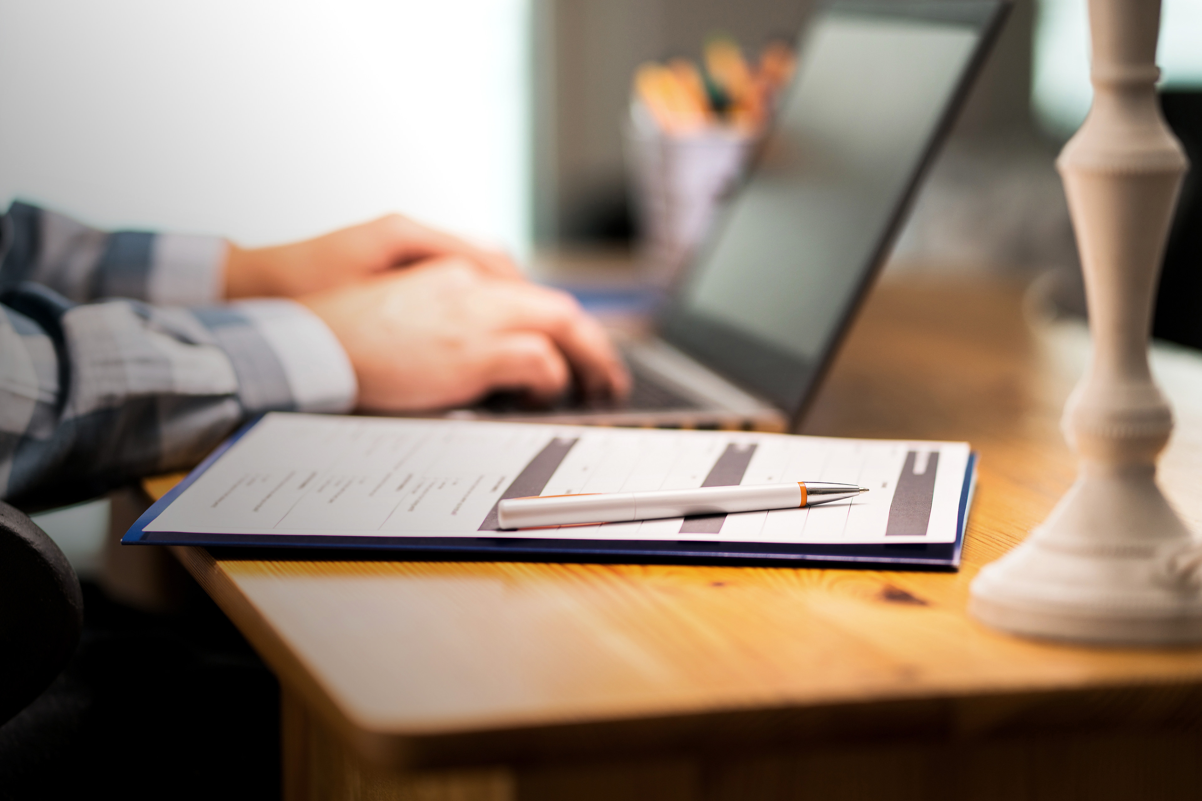 Man writing with laptop next to survey form