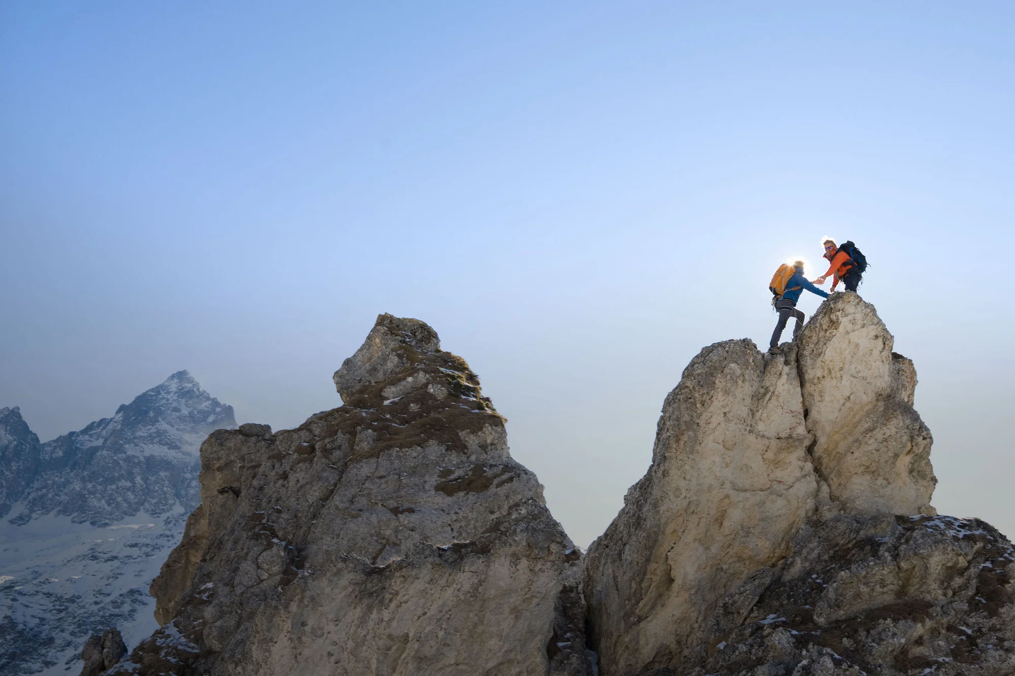 hiker woman helping her friend reach the top of the mountain