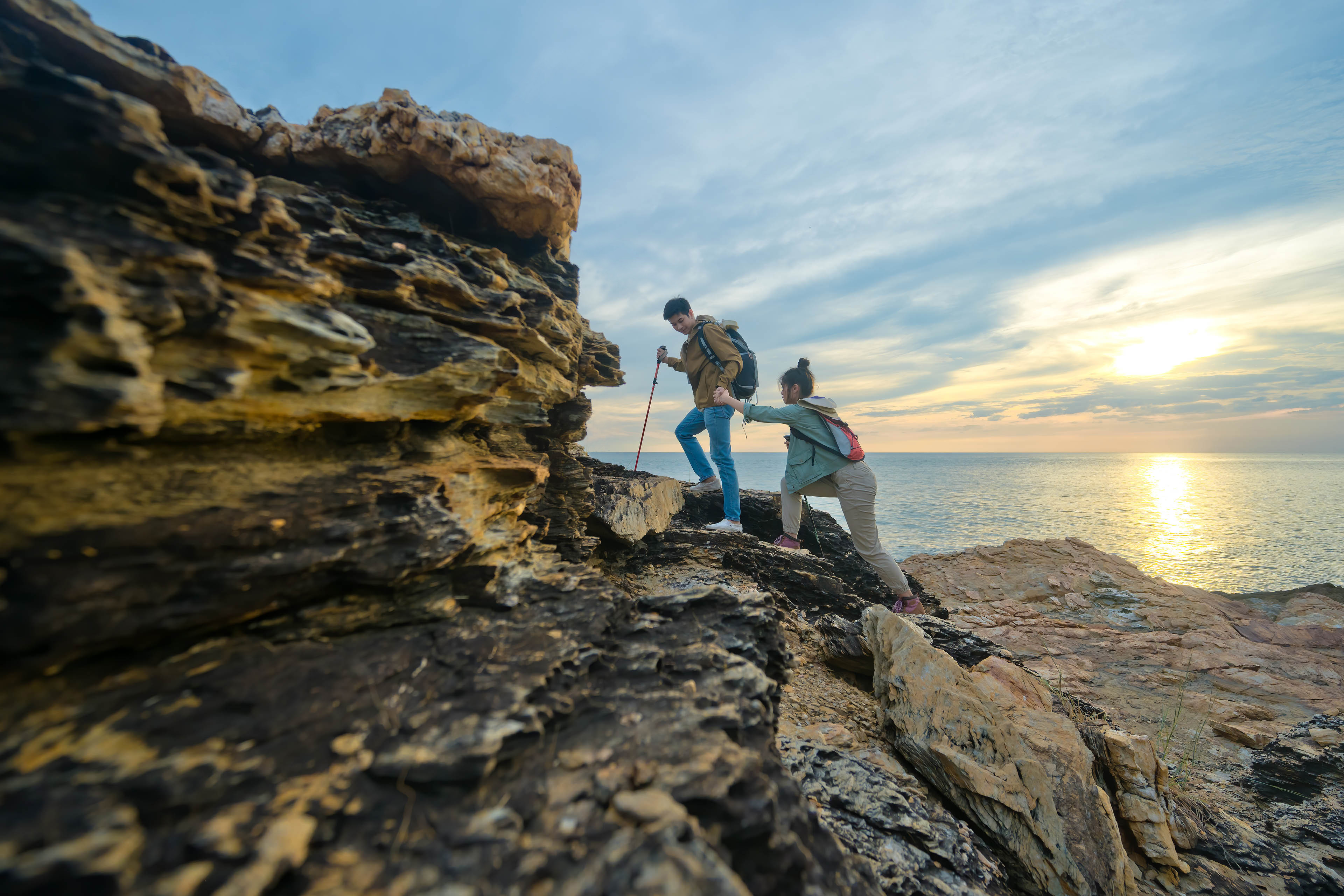 Young Asian couple climbing up the cliff