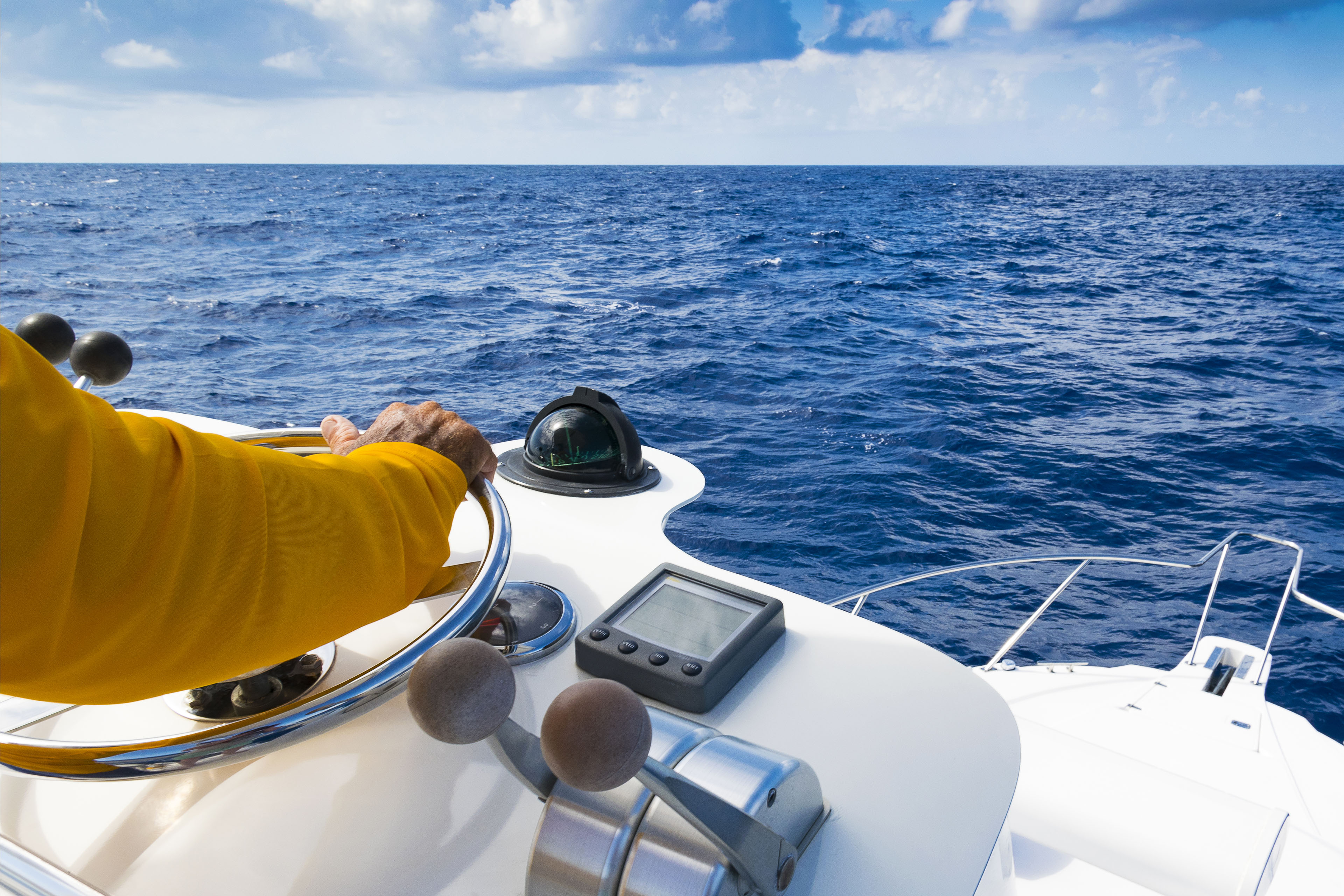 Captain in yellow jacket steering a yatch