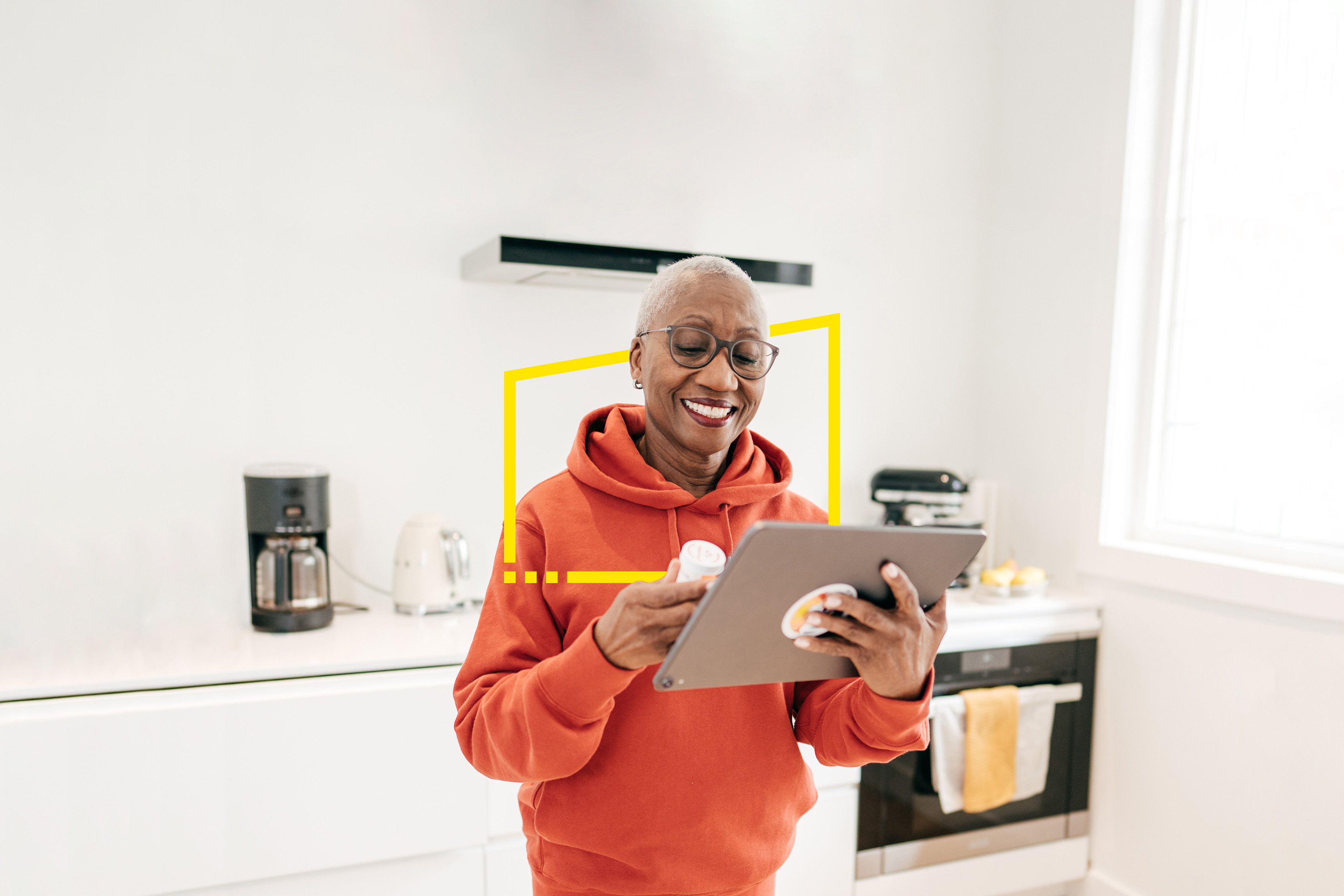 Woman checking medication on tablet device in kitchen