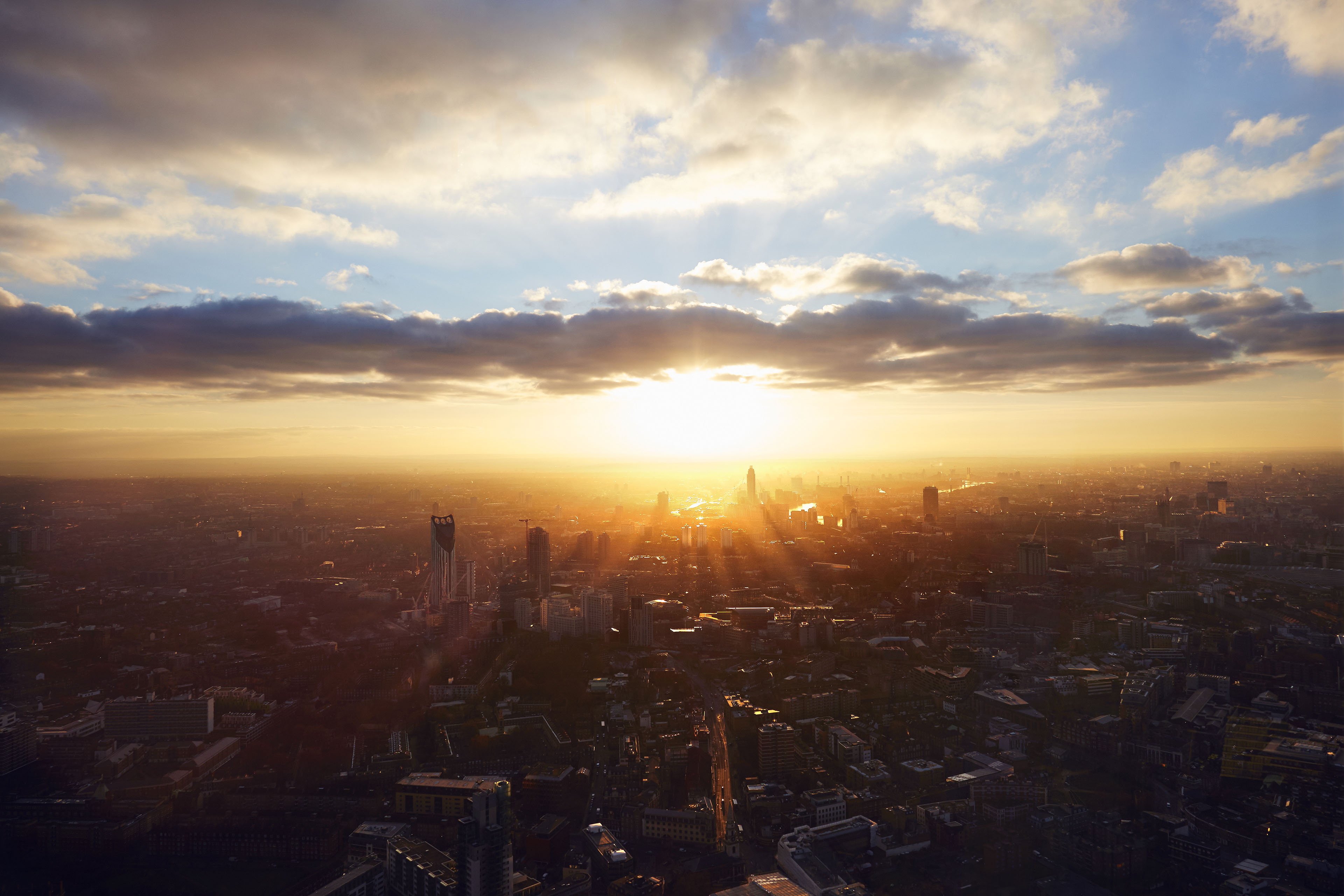 The sun rises through the city on a misty morning