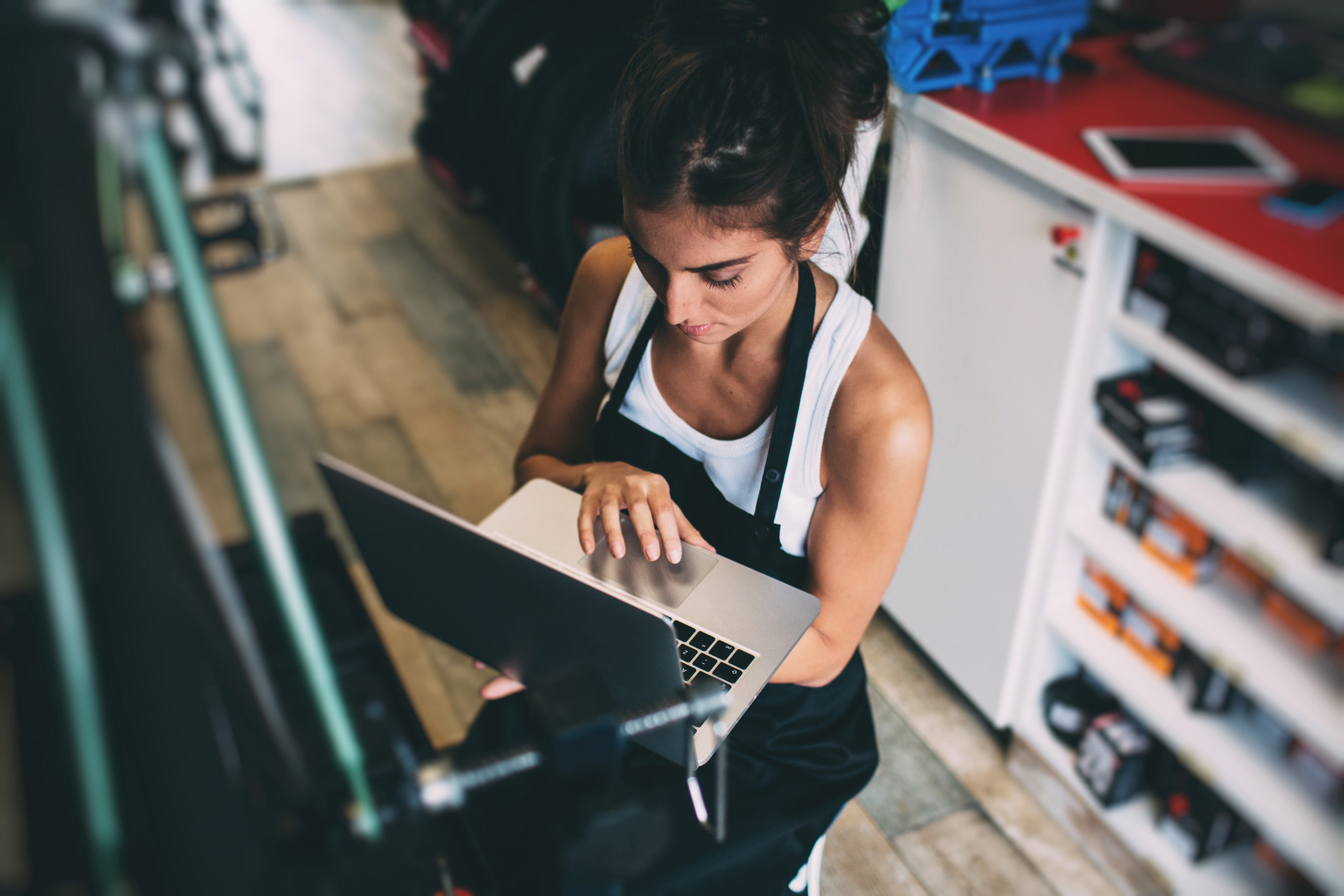 Woman holding a laptop in one hand and operating it with the other