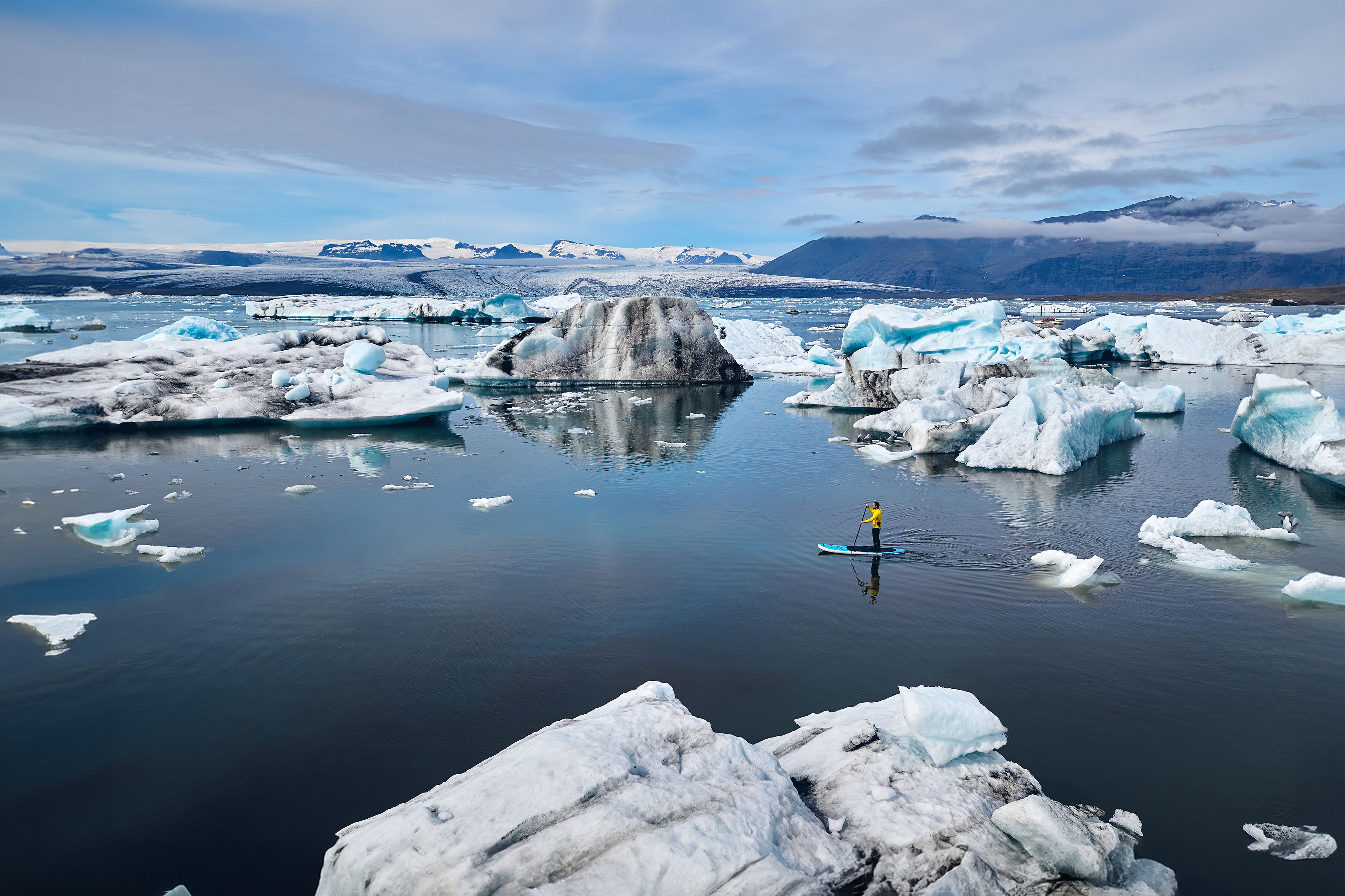 Man stand up paddle boarding through glacier lagoon in Iceland