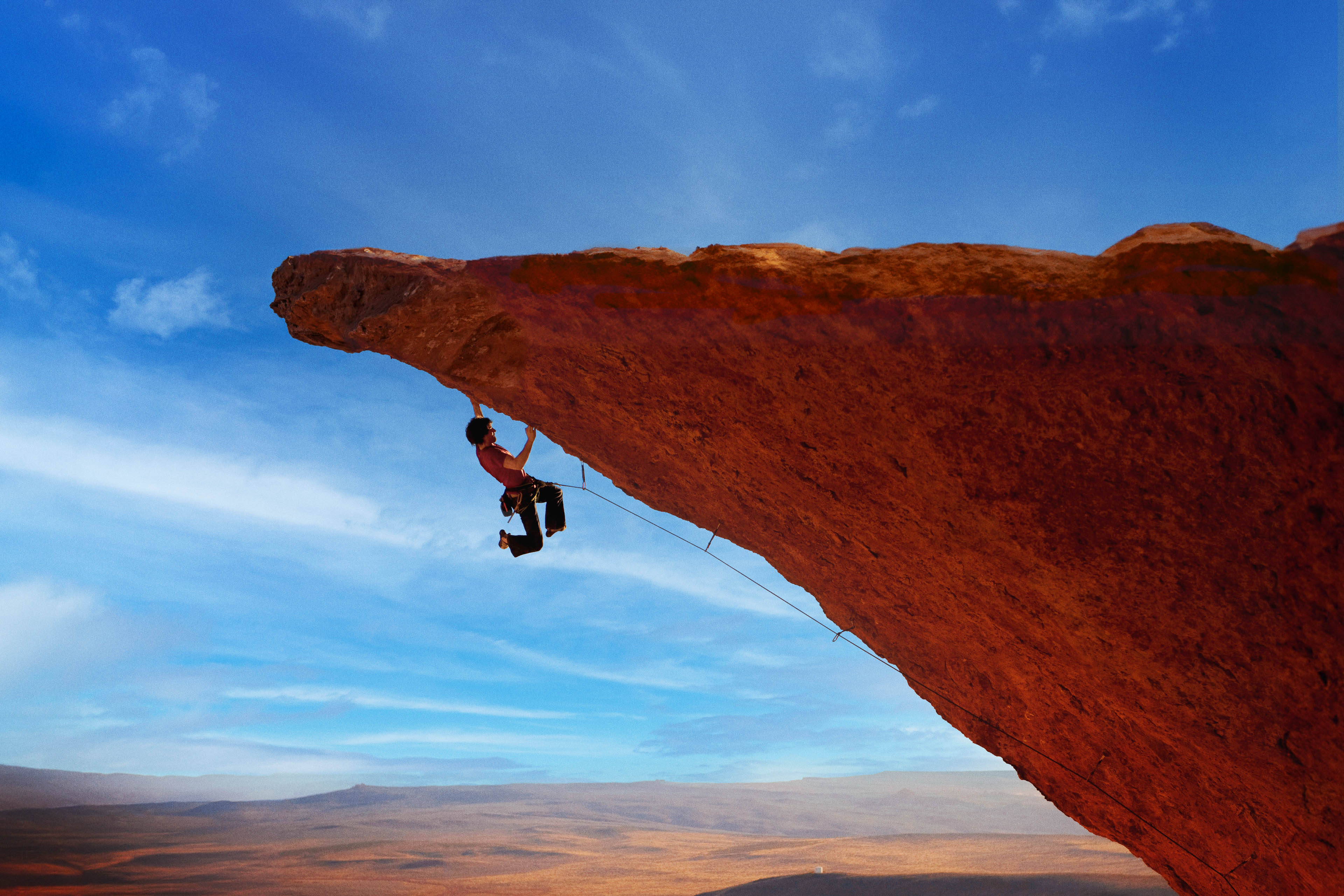 Rock climber lunging for a hand hold rock wall in South West Utah