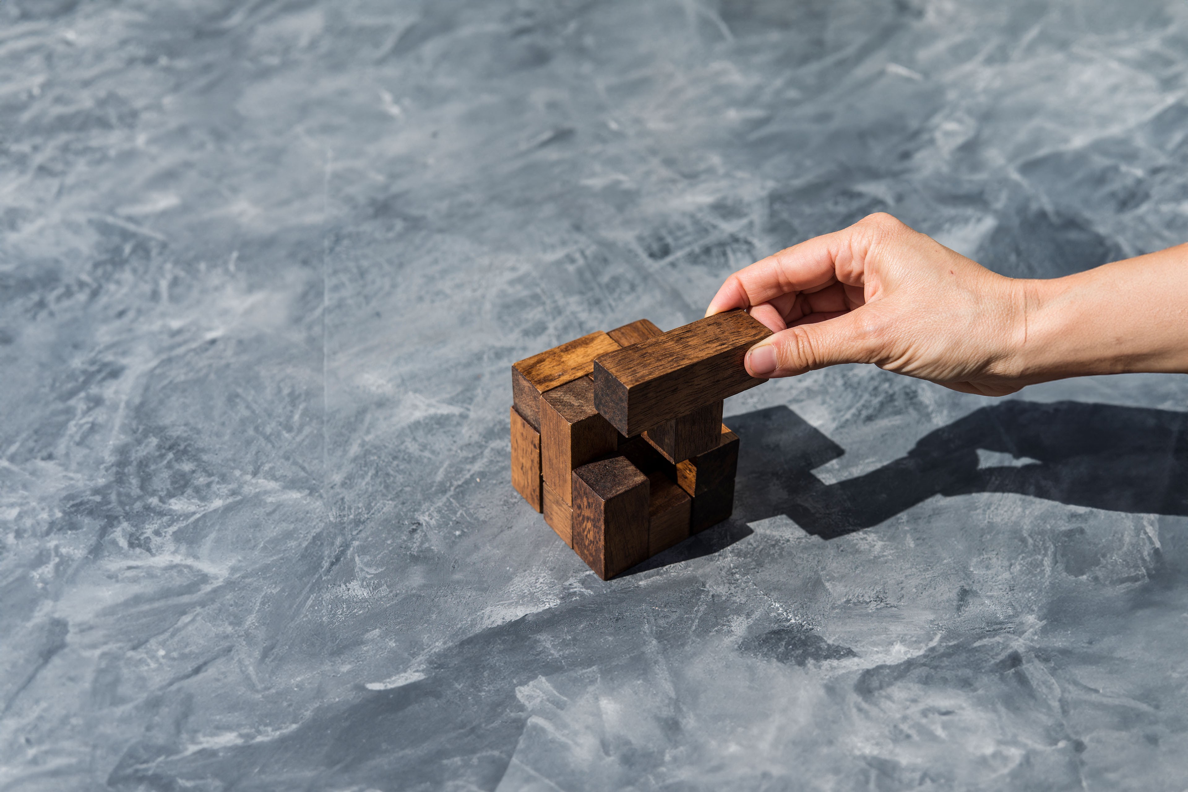 Hand of woman assembling pieces of wooden puzzle