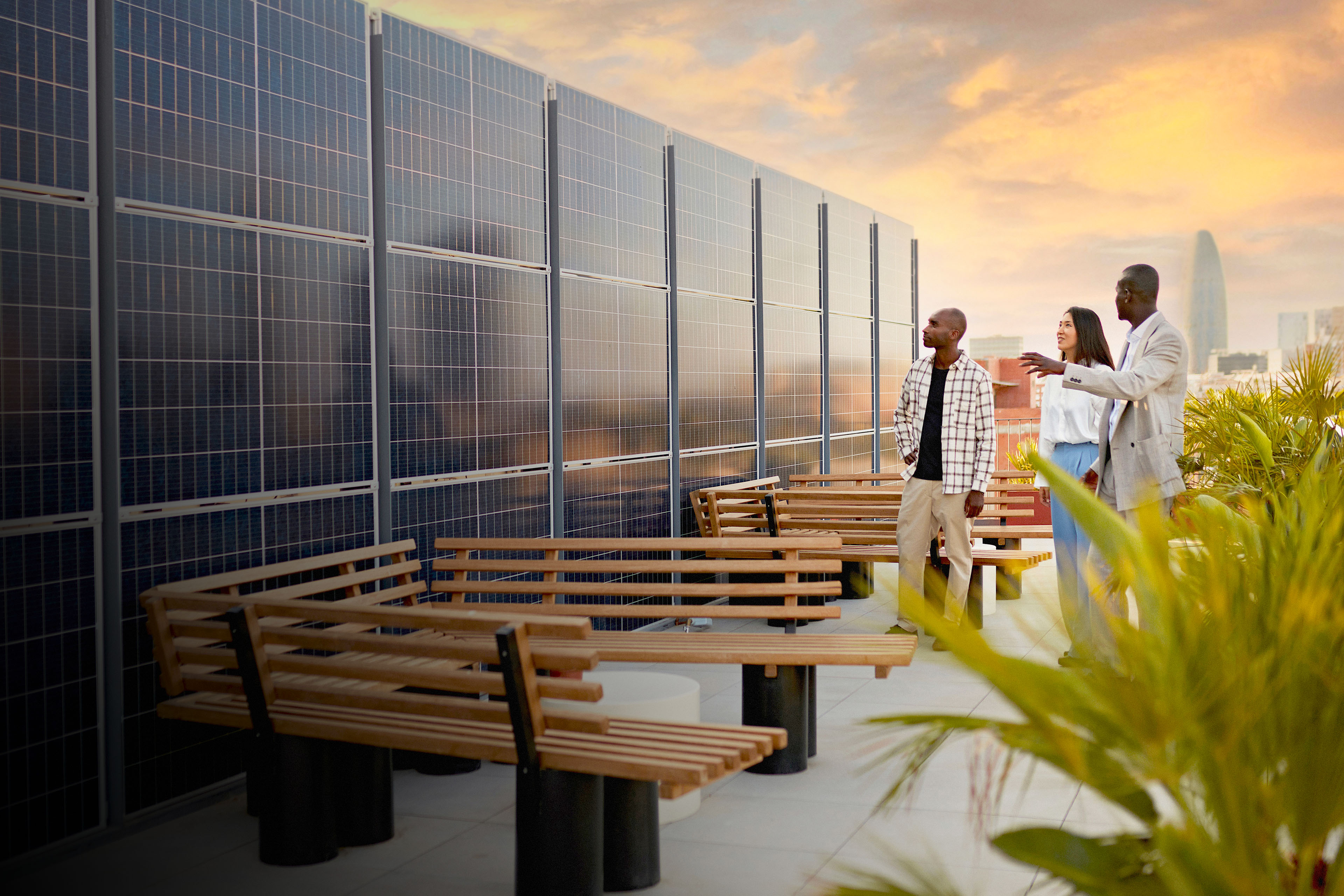 Real estate agent and couple standing on rooftop of environmentally aware office building with dramatic sky