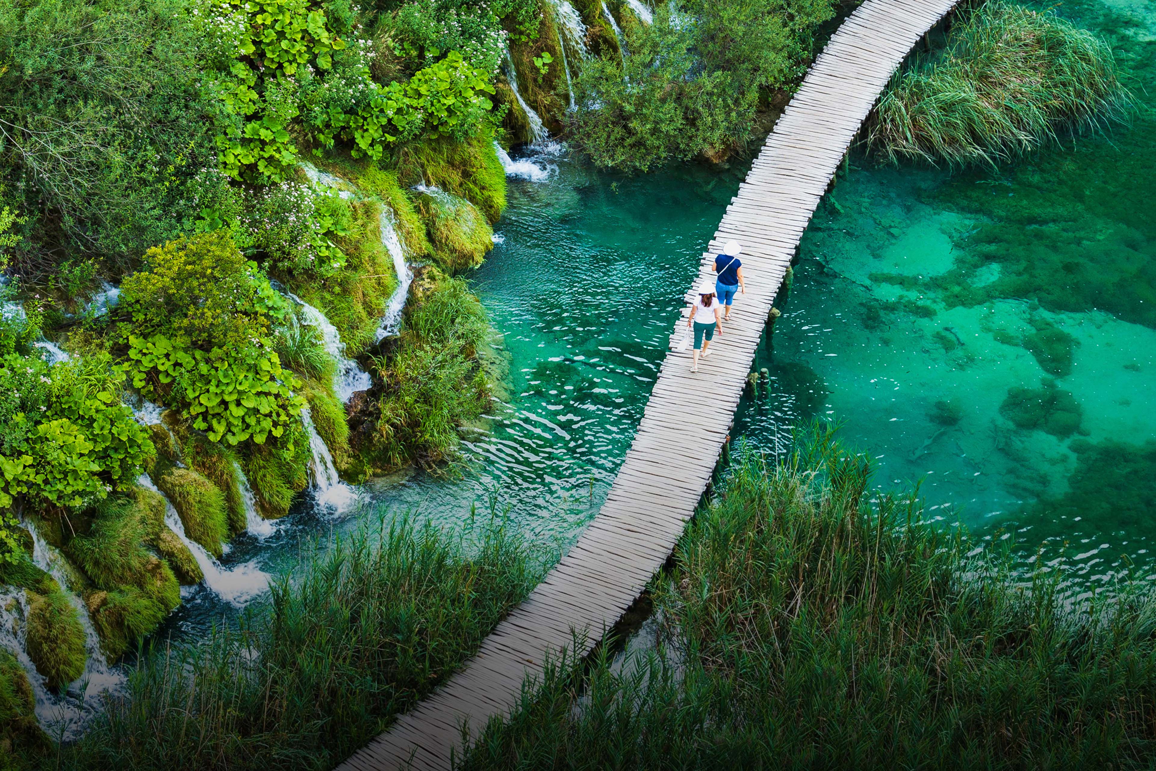 Tourists walk by wooden path, in the Plitvice Lakes National Park