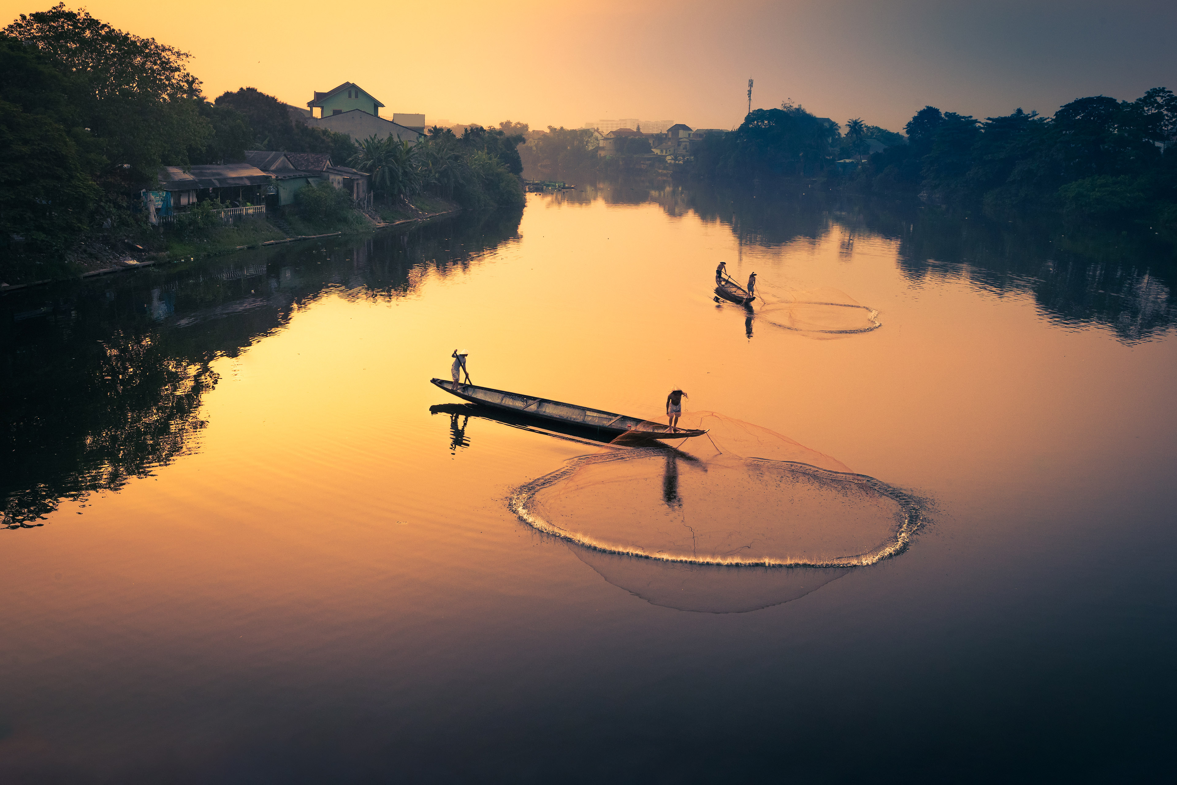 Fishermen in a traditional rowboat throwing the fishing net