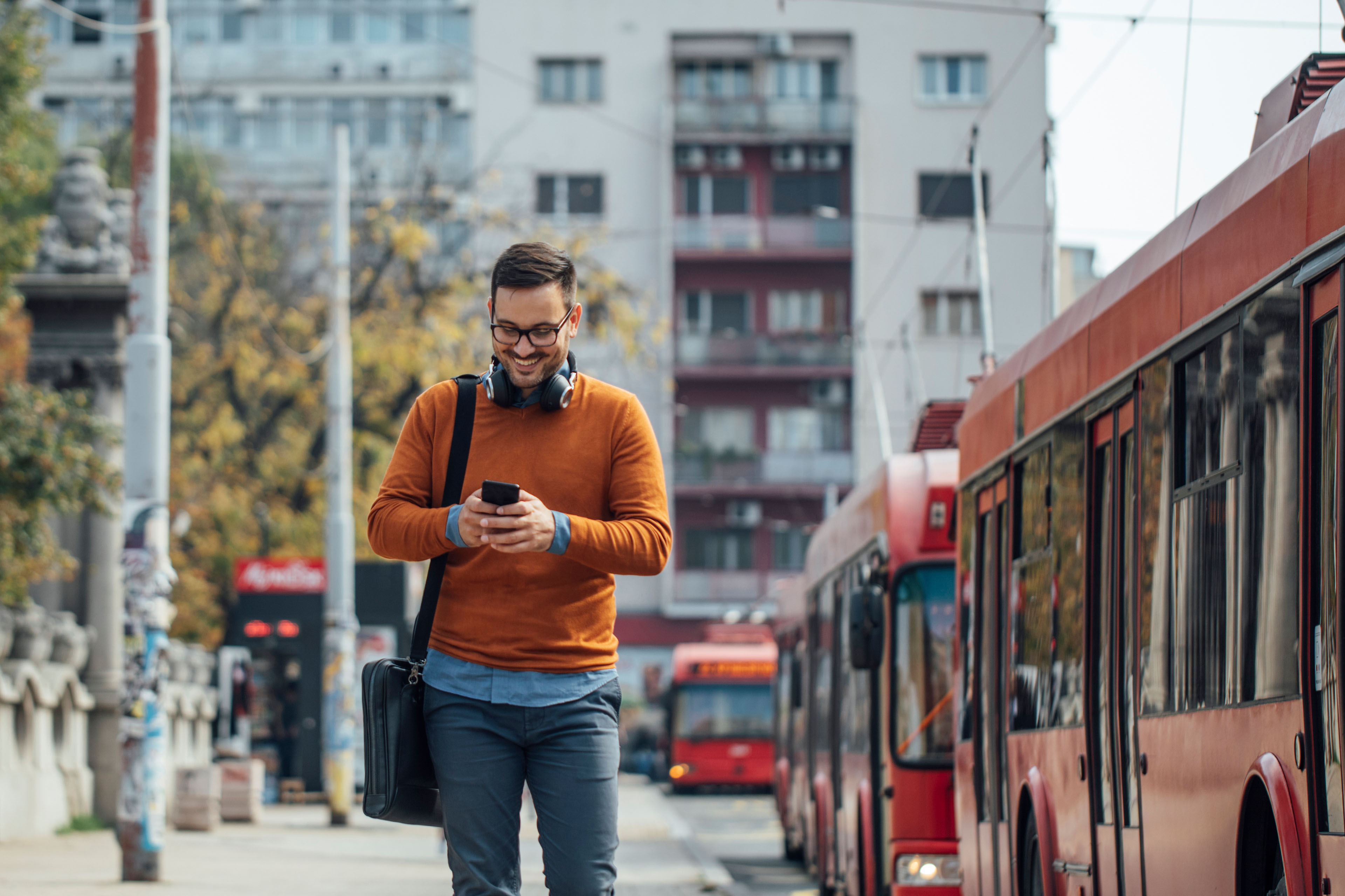 Happy businessman working on the street by using his smartphone