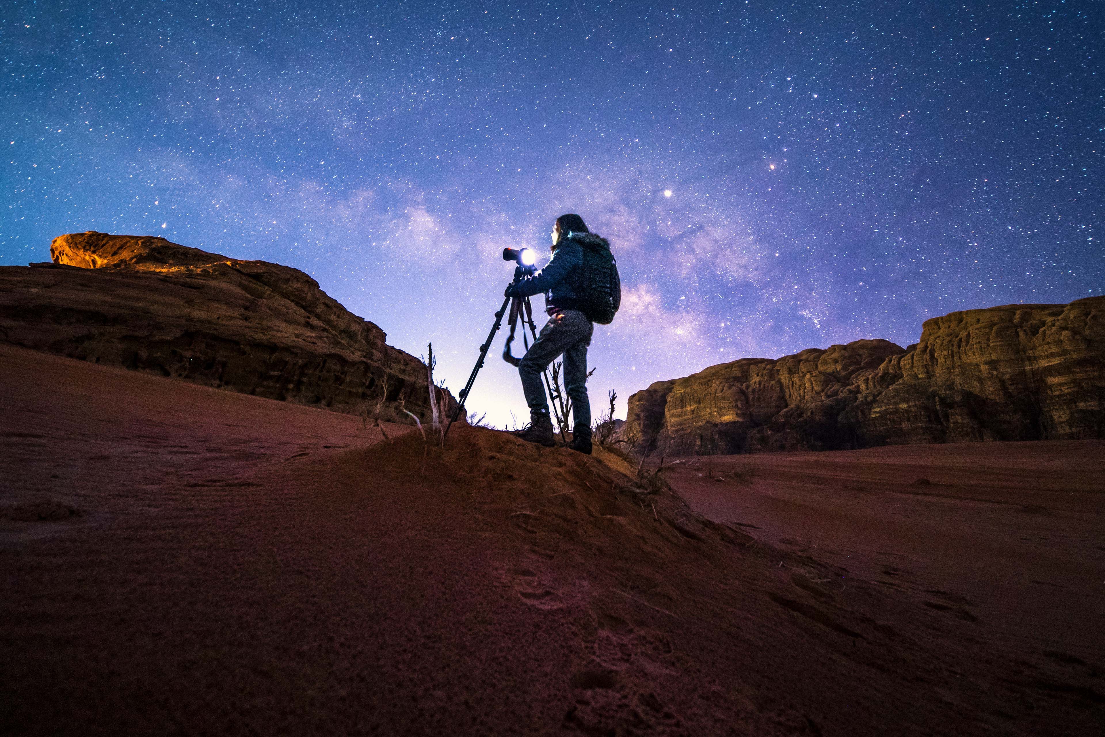 Photographer in wadirum desert under the milky way