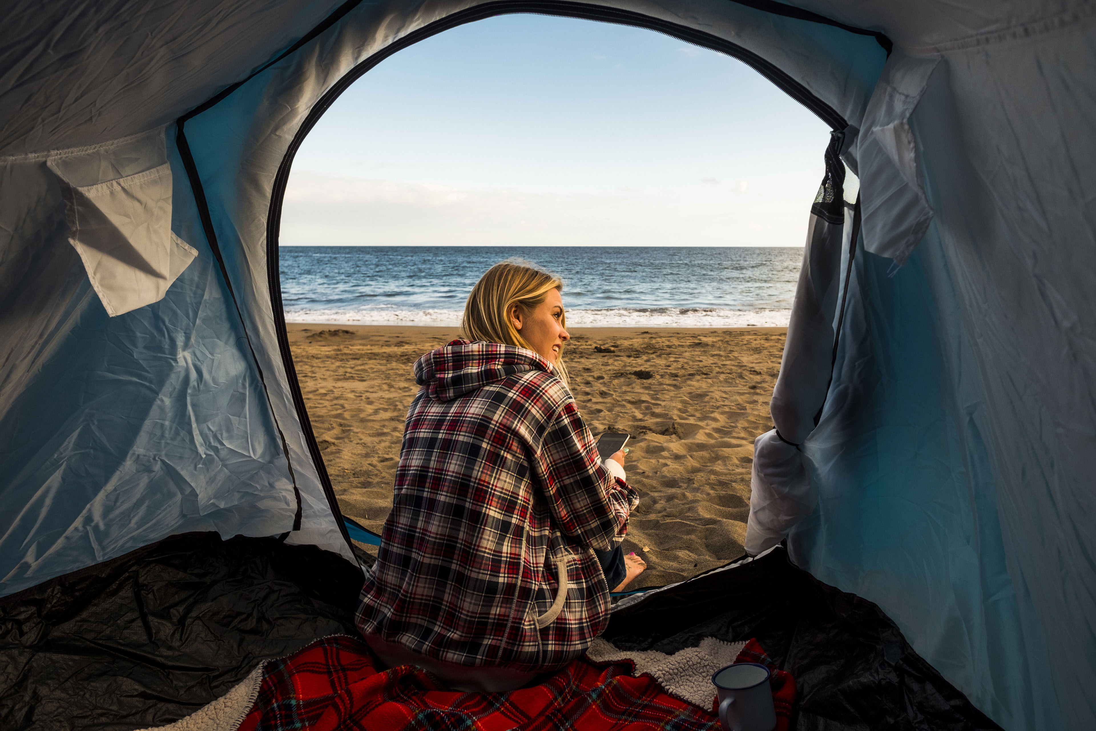 Woman sitting in her tent on the beach