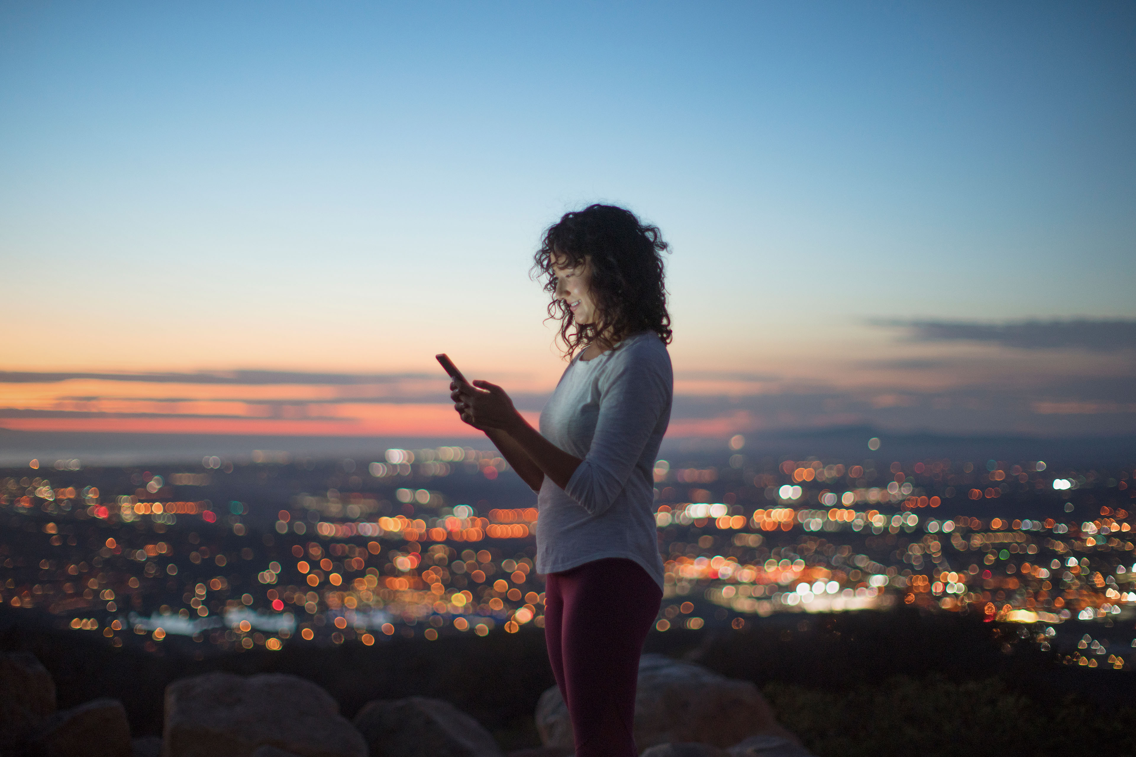 Young woman texting on her phone at night