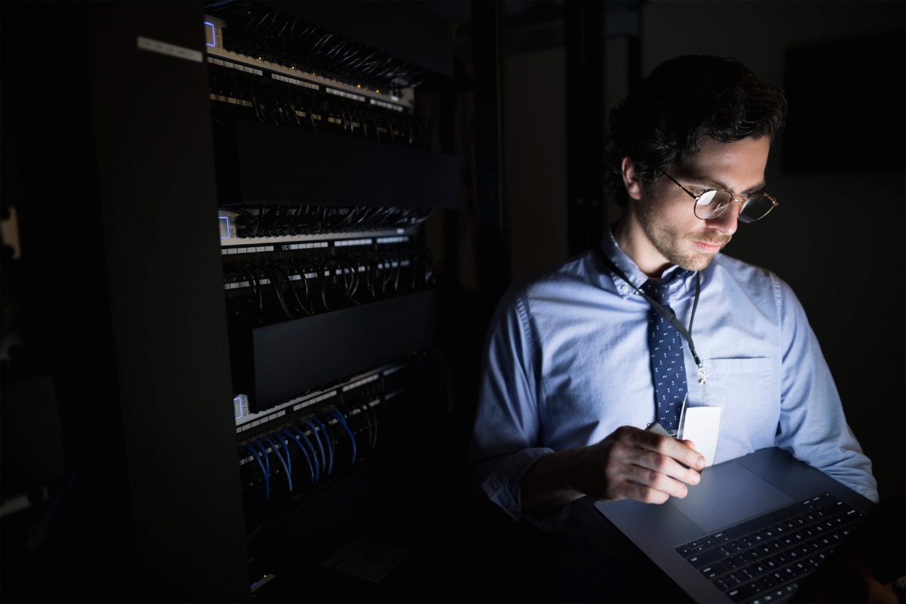  Hombre de EY mirando tablet en una sala de servidores oscura