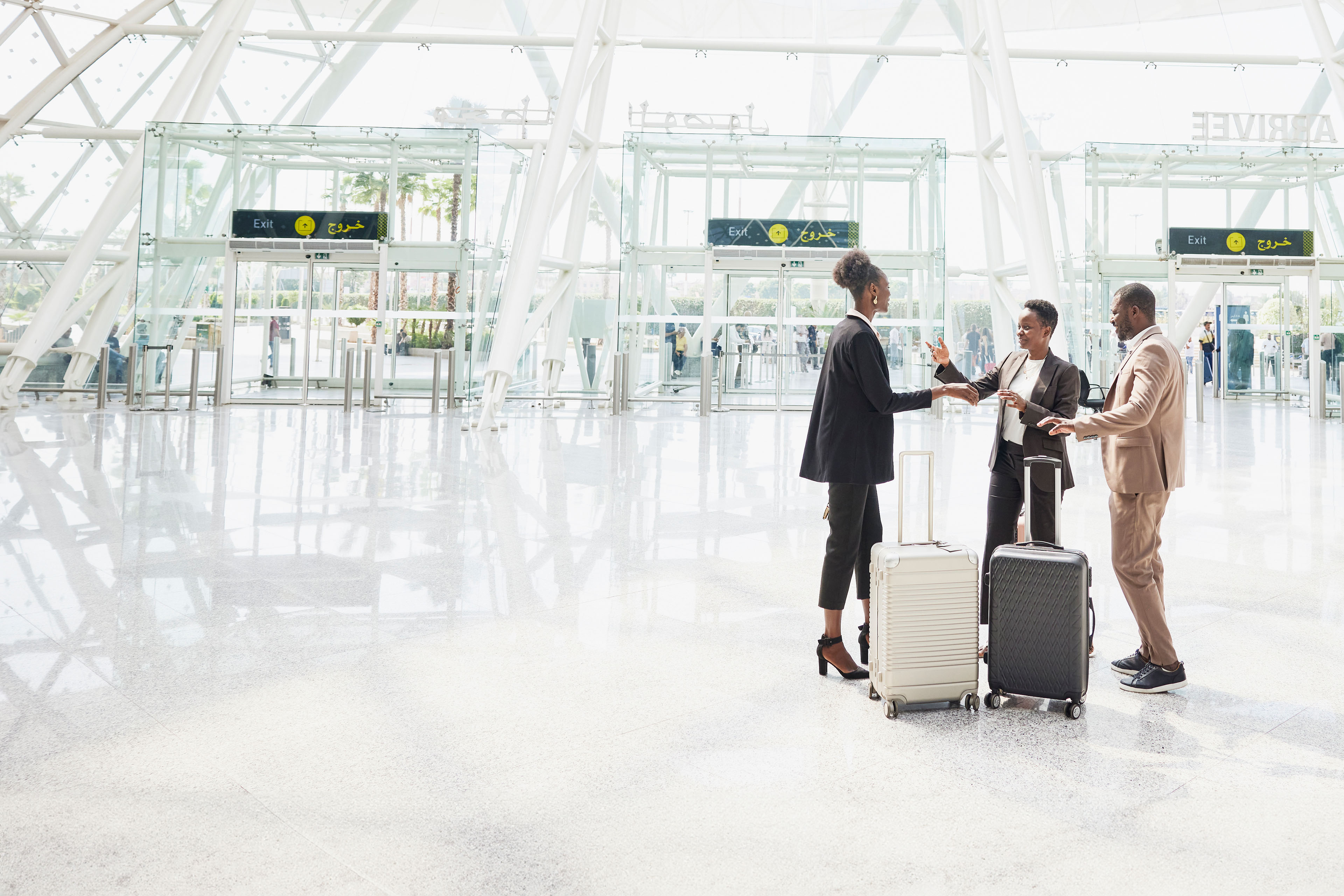 Wide shot business colleagues greeting in airport arrival terminal