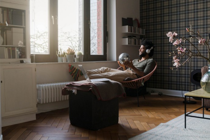 Man sitting in living room in armchair holding mirror ball listening to music