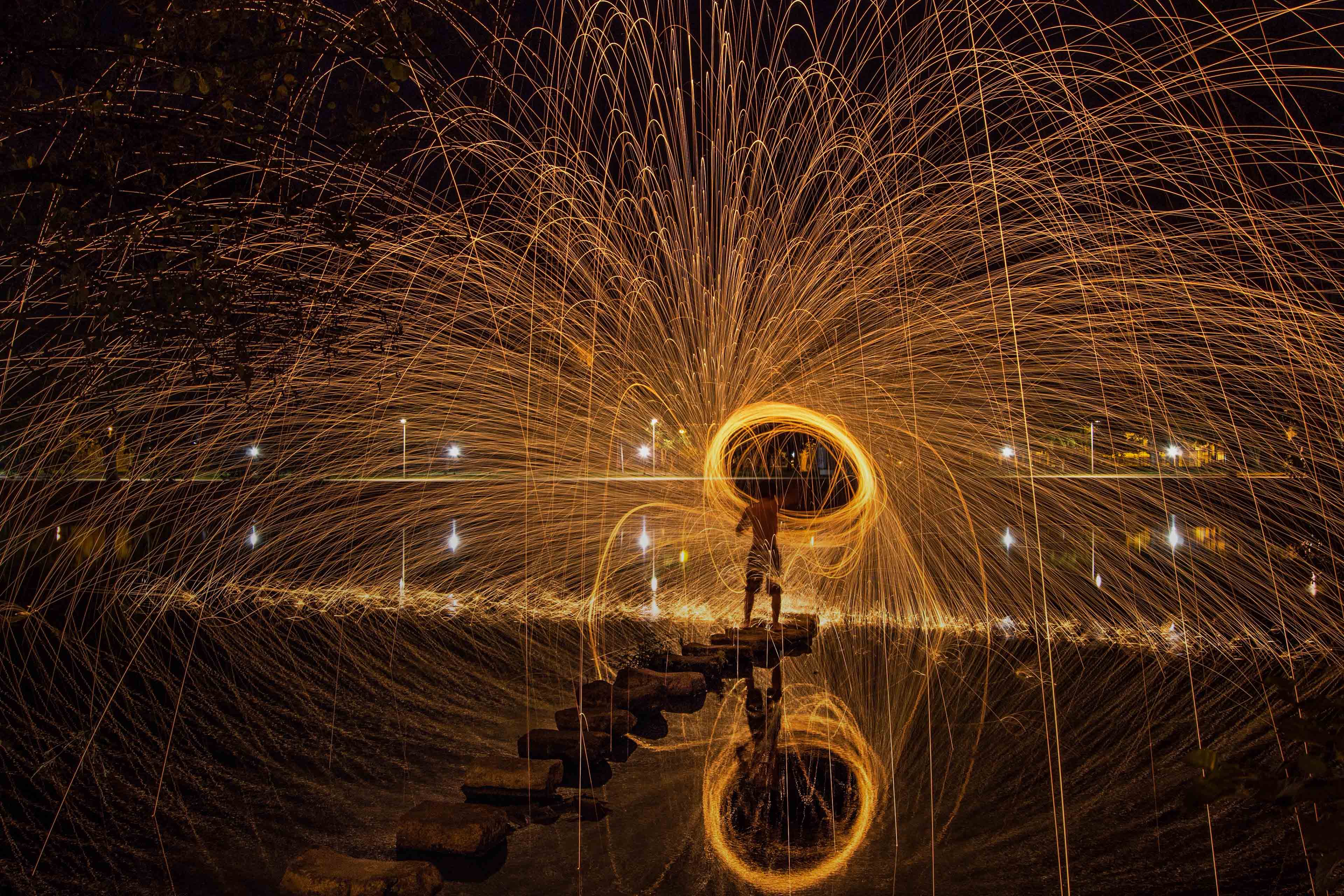 Man spinning wire wool at night