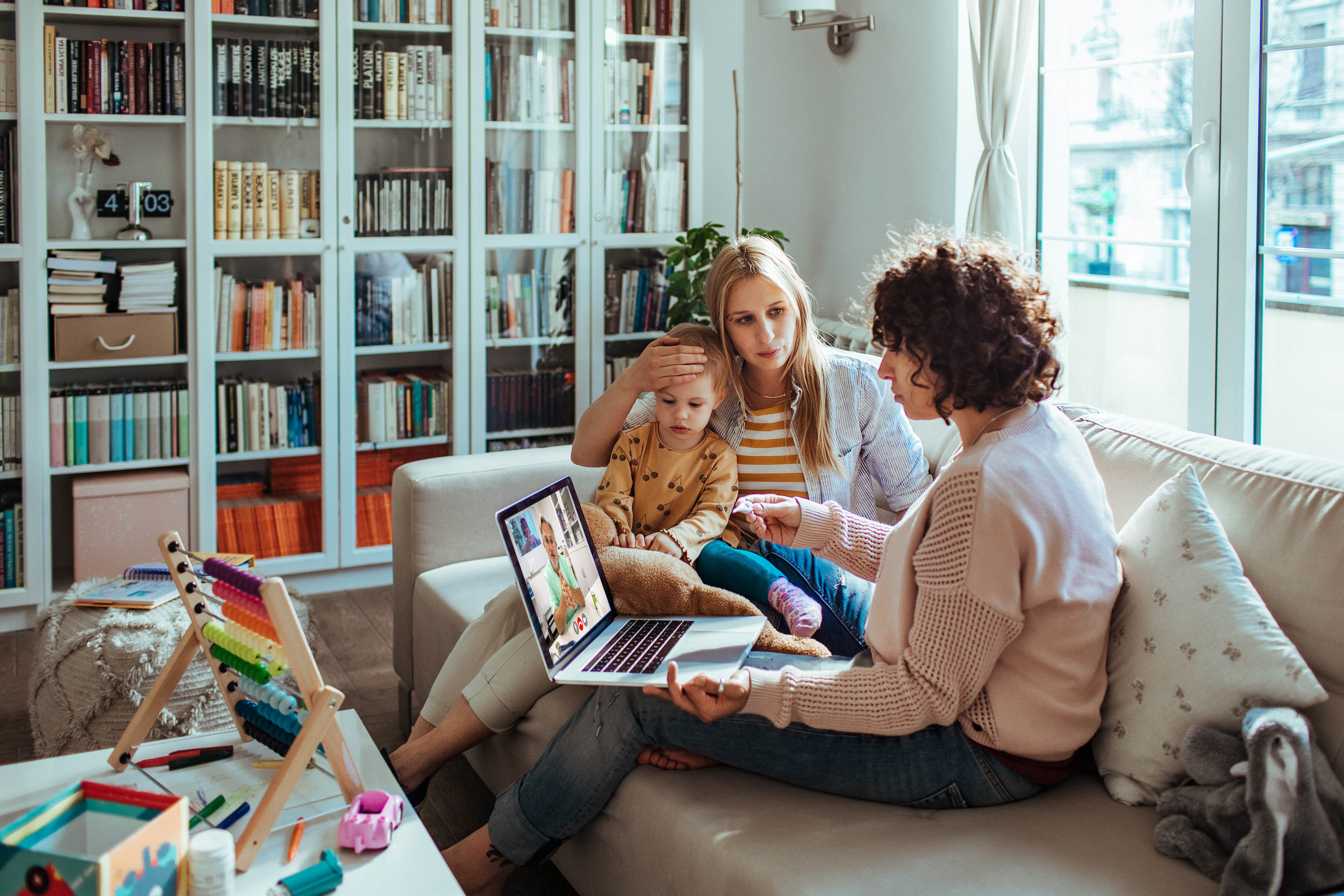 Close up of a young family on a video call with their doctor