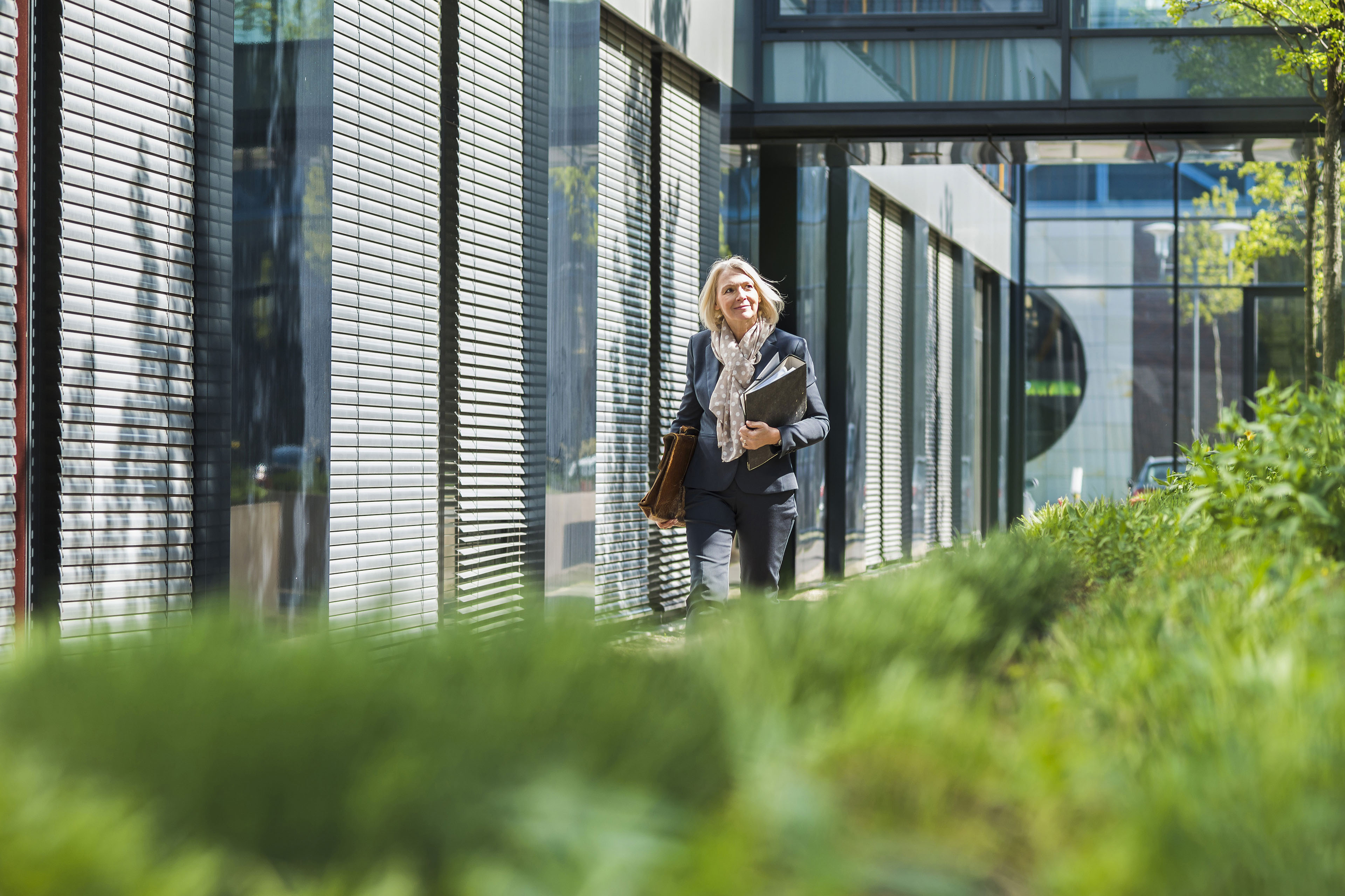 Businesswoman carrying briefcase and files past office