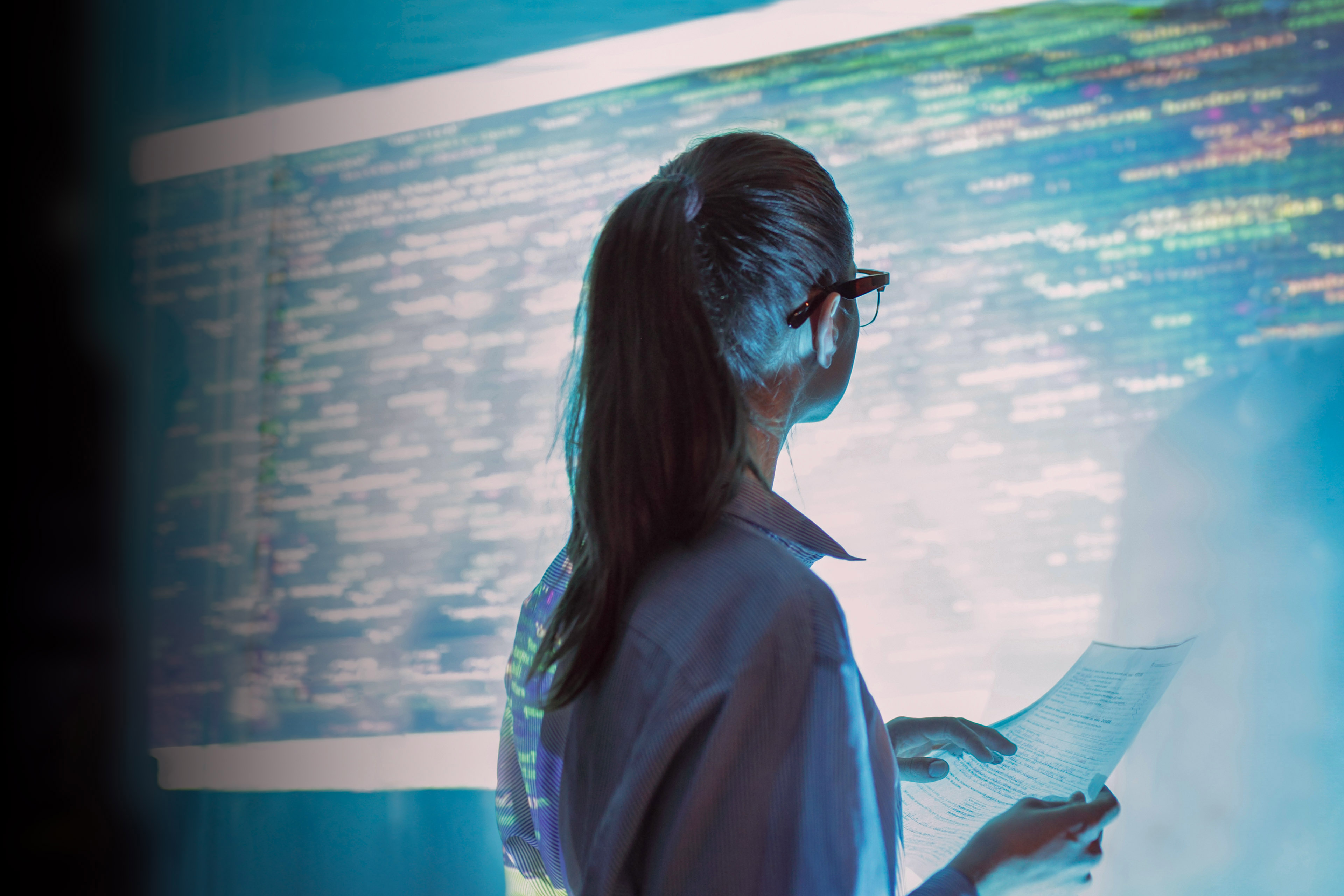 Woman looking at projected code on office wall