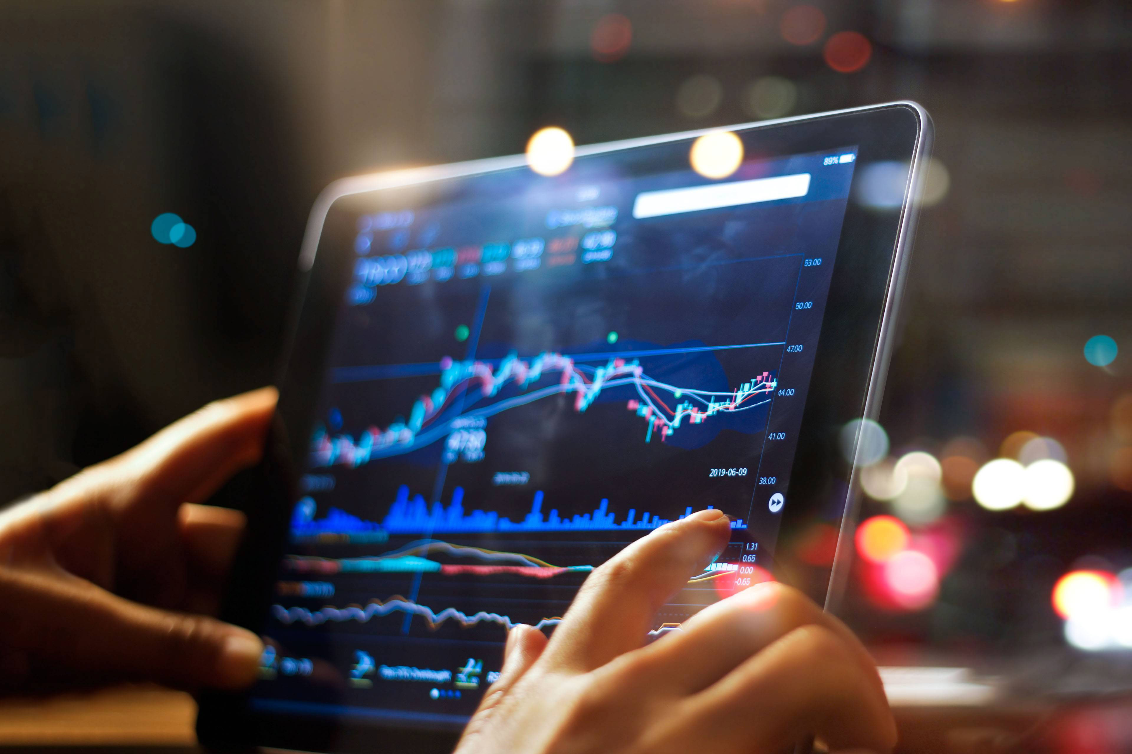 Businessman checking stock market data on tablet on night background