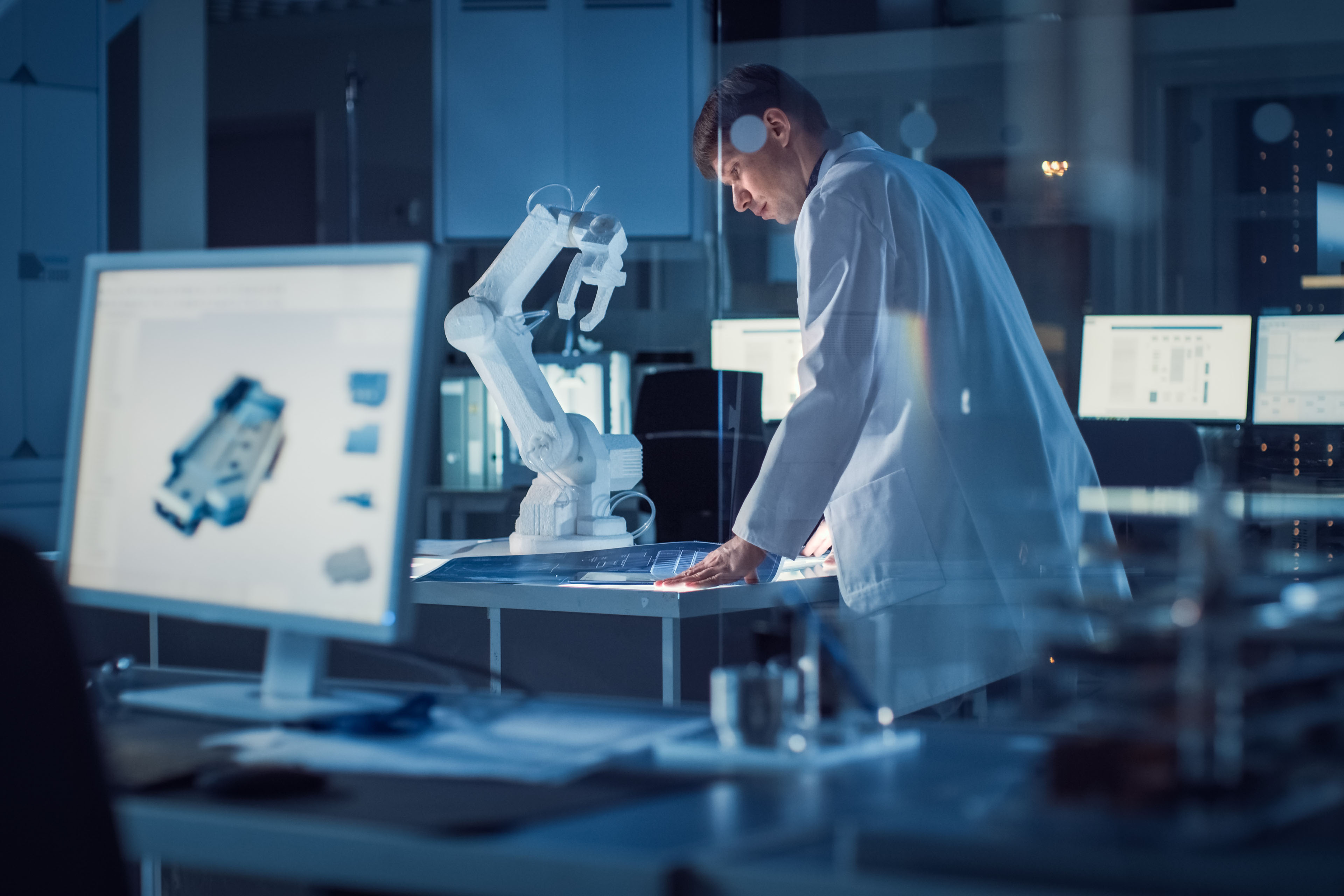 Robotics engineer wearing white coat reviewing designs in lab