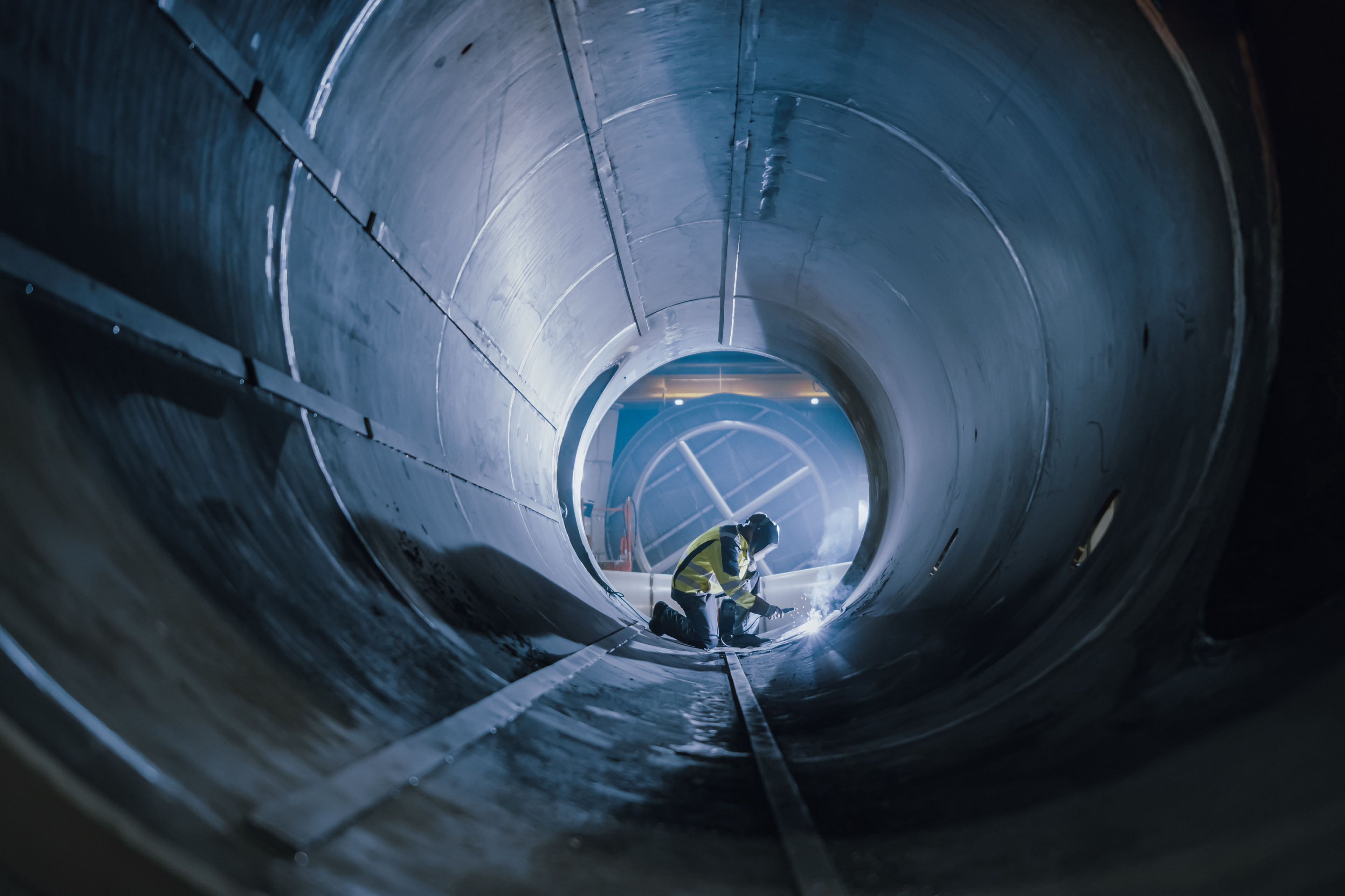 Industry worker wearing helmet welding inside oil and gas pipe