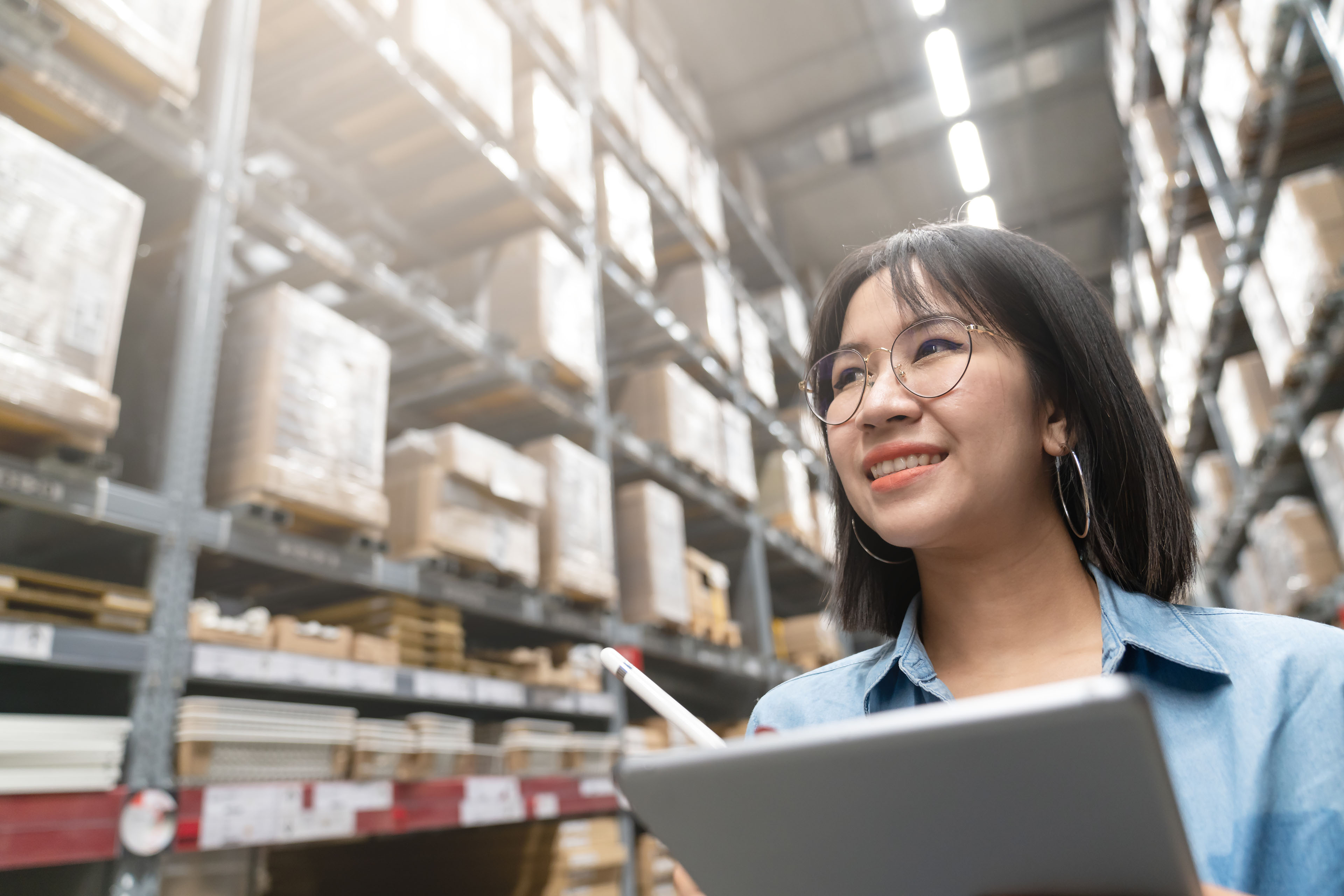 Asian woman uses tablet to check stock in warehouse