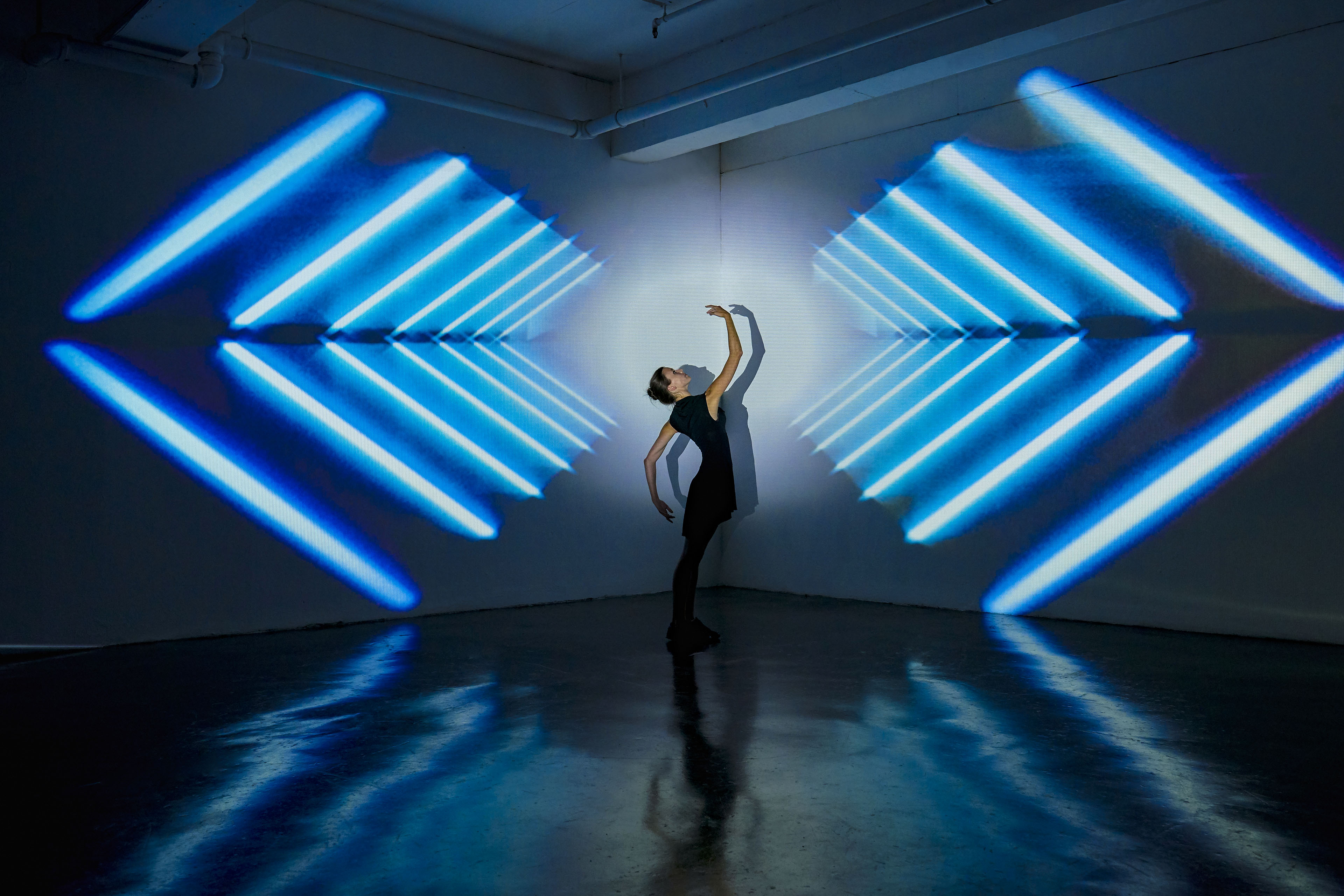 Girl dancing in a studio with graphic patterns projected onto wall behind