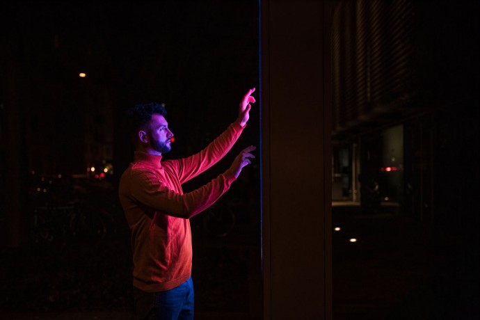 Man using touch screen kiosk machine on street at night