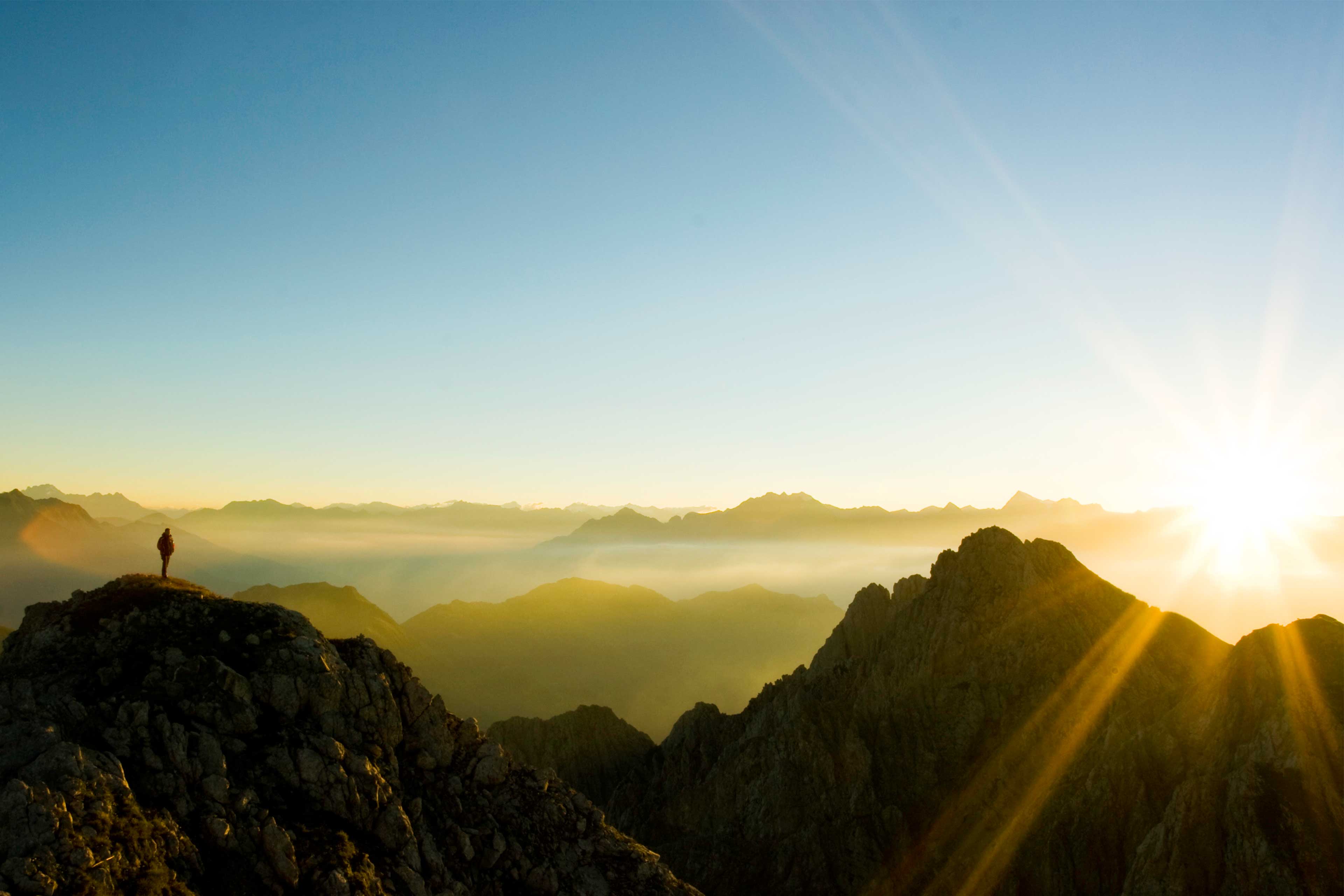 Man watching the sunrise by standing on top of the hill