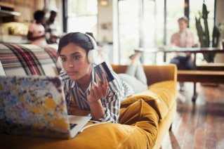 Young lady working in Laptop by holding card and wearing Headphones